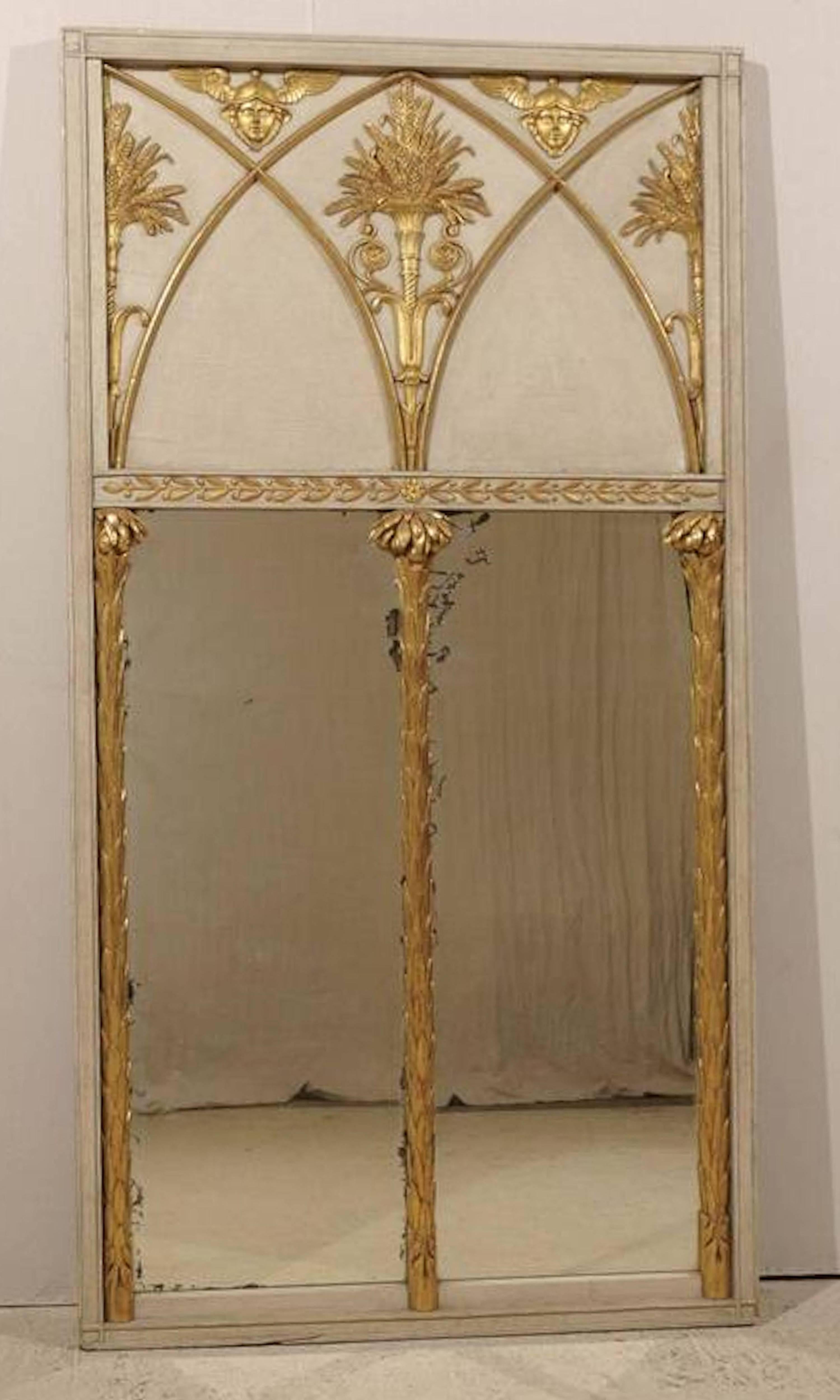 Exceptional and unusual French Directoire period trumeau mirror of monumental scale having original painted and parcel-gilt frame with neoclassical and foliate ormolu appliqués in the forms of winged Mercury heads, wheat-sheaves, and flowering