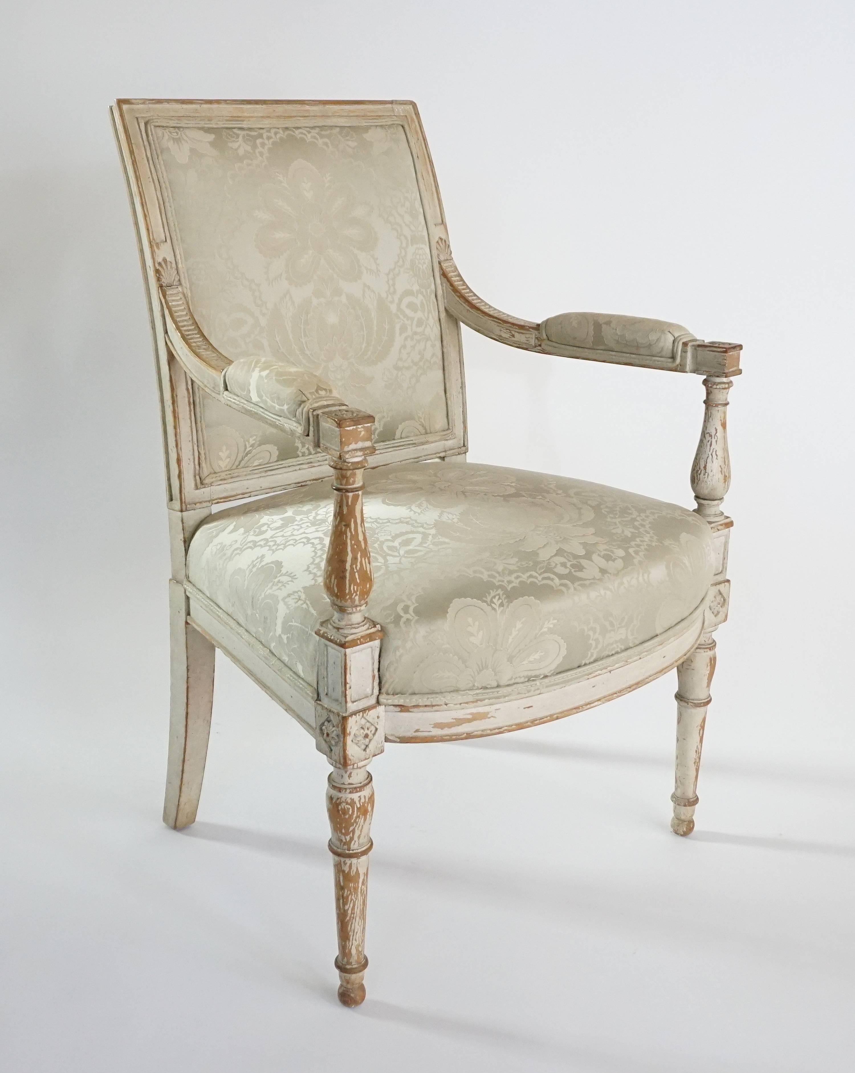 A circa 1795 French Directoire fauteuil or armchair having original painted carved wood frame with rectangular upholstered back issuing acanthus and reeded arms with padded armrests ending in square rosette-in-lozenge terminals joining baluster