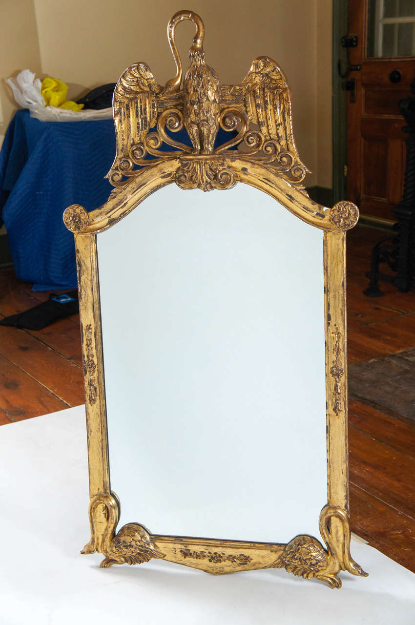 Unusual first quarter of the 20th century Italian wall mirror or looking glass having carved giltwood frame with arched pediment and large spread-winged swan, acanthus corner rosettes and double opposing swans at bottom.