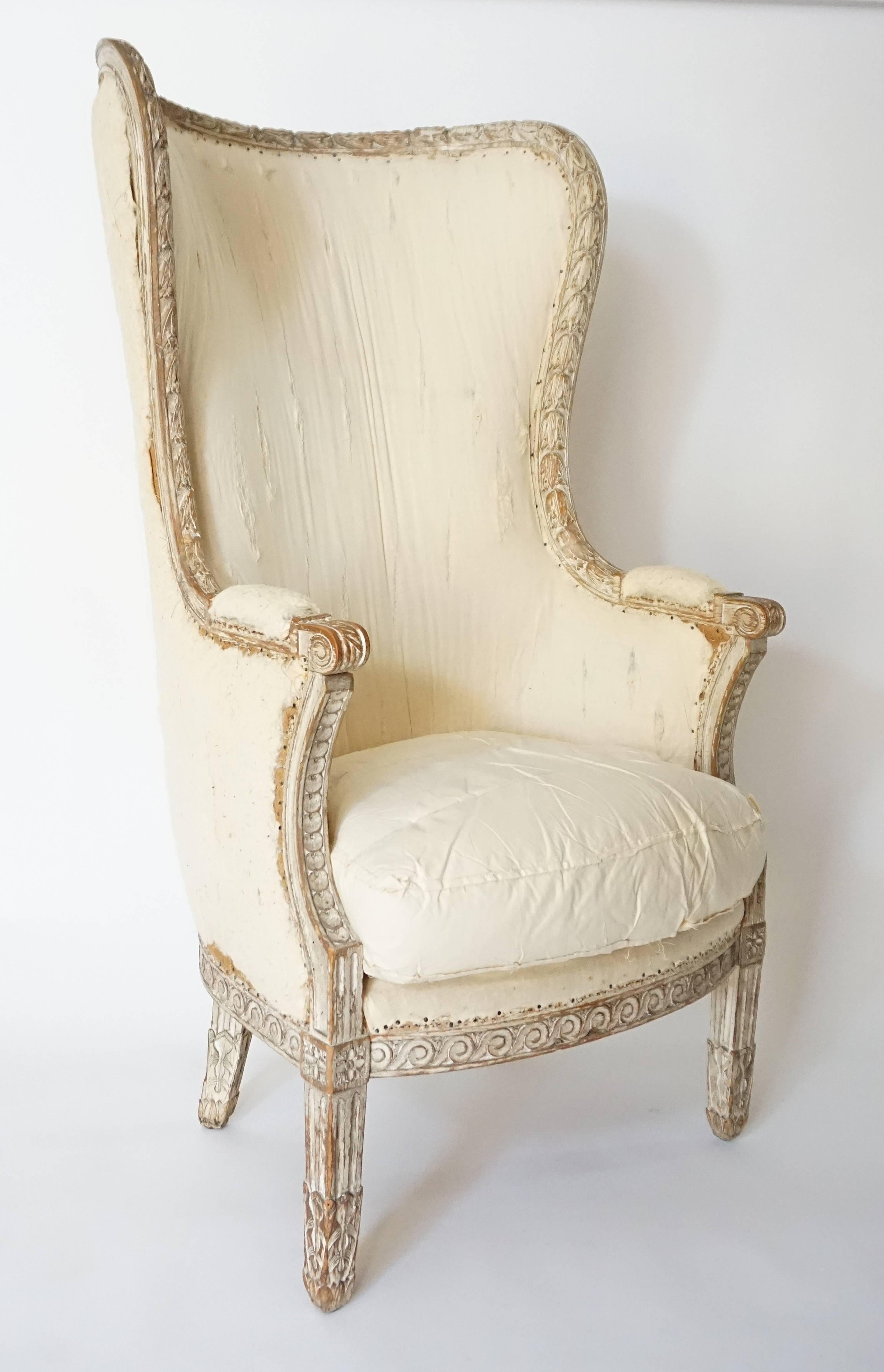 An exceptional circa 1770 French, Louis XVI period bergère a' oreilles or wingback with back, arms, seat, and down-filled squab cushion upholstered and original painted frame with carved acanthus garland border around curved wing-back terminating