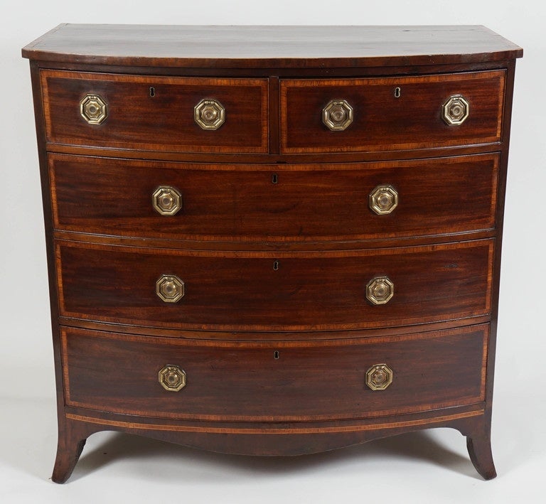 George III period, Hepplewhite style cross-banded mahogany chest of drawers of bow-front form having two upper drawers and three lower all with original octagonal form bail-pull brass hardware surmounting shaped apron joining splayed French feet. A