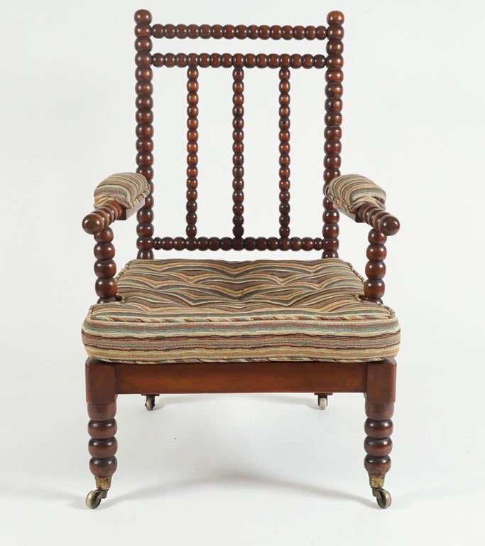 English, circa 1840 mahogany bobbin-turned armchair / chair having double turned crest-rail and triple spindle-splat back adjoining turned arms with thickly padded rests and caned seat with squab tufted cushion on front turned legs and rear splayed,