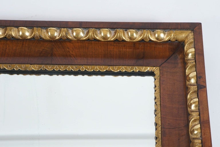 Elegant circa 1820 Austrian Biedermeier mirror having walnut cove-mould frame with carved giltwood lamb's tongue and egg-and-dart fillets around original silvered mirror plate.