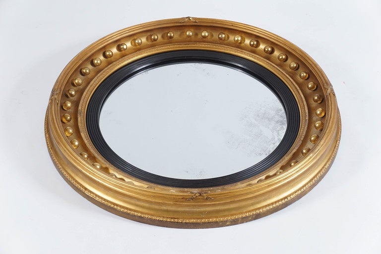 An unusually large English Regency style, William IV period, circa 1835 'bullseye' giltwood mirror of round form having antique flat mirror plate within an ebonized reeded rabbet and gilt lamb's tongue moulded edge followed by a concave moulding