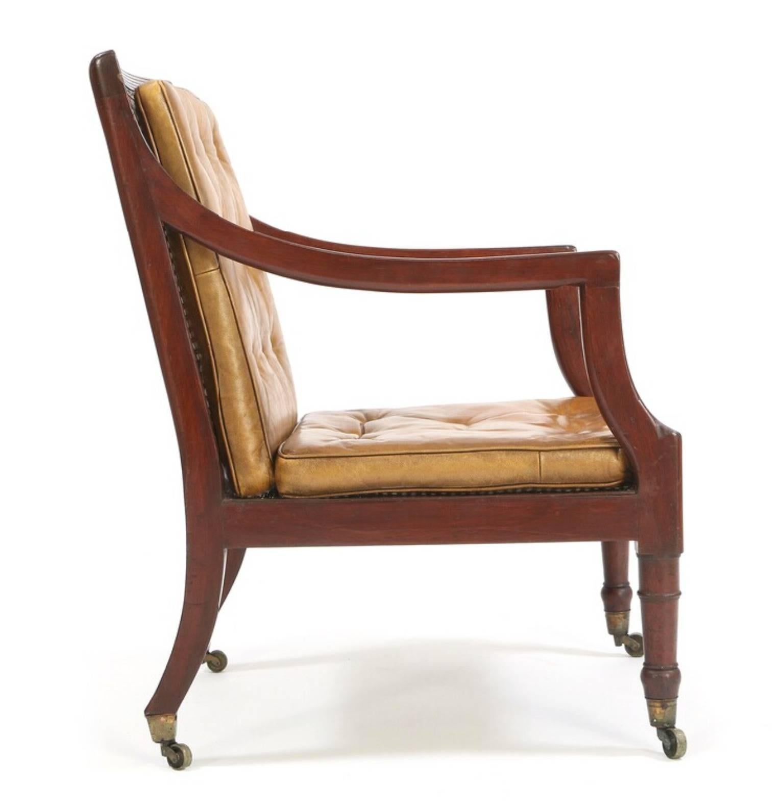 Fine George III, early English Regency period, circa 1800 armchair or library chair of elegant, clean design having solid mahogany frame with rectangular caned back, open arms, and caned seat with loose tufted leather cushions on turned front legs