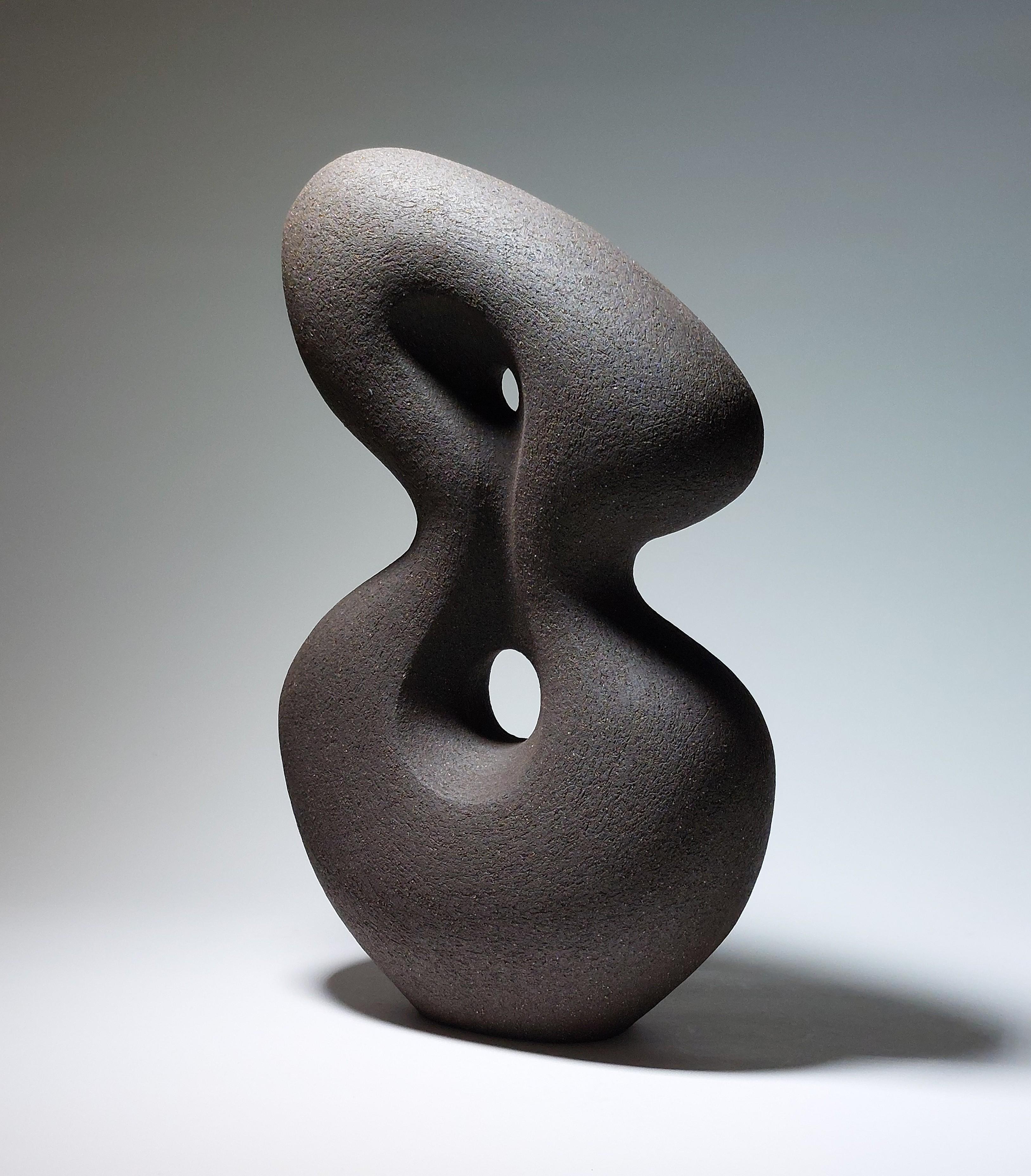 Poise - Scultura astratta in ceramica nera di Rachel Peters, Regno Unito, non smaltata,  In magazzino.

In Poise, Rachel Peters esplora la forza che si trova nell'equilibrio e nel gesto sottile. Arrotolata a mano in gres nero, la scultura si erge