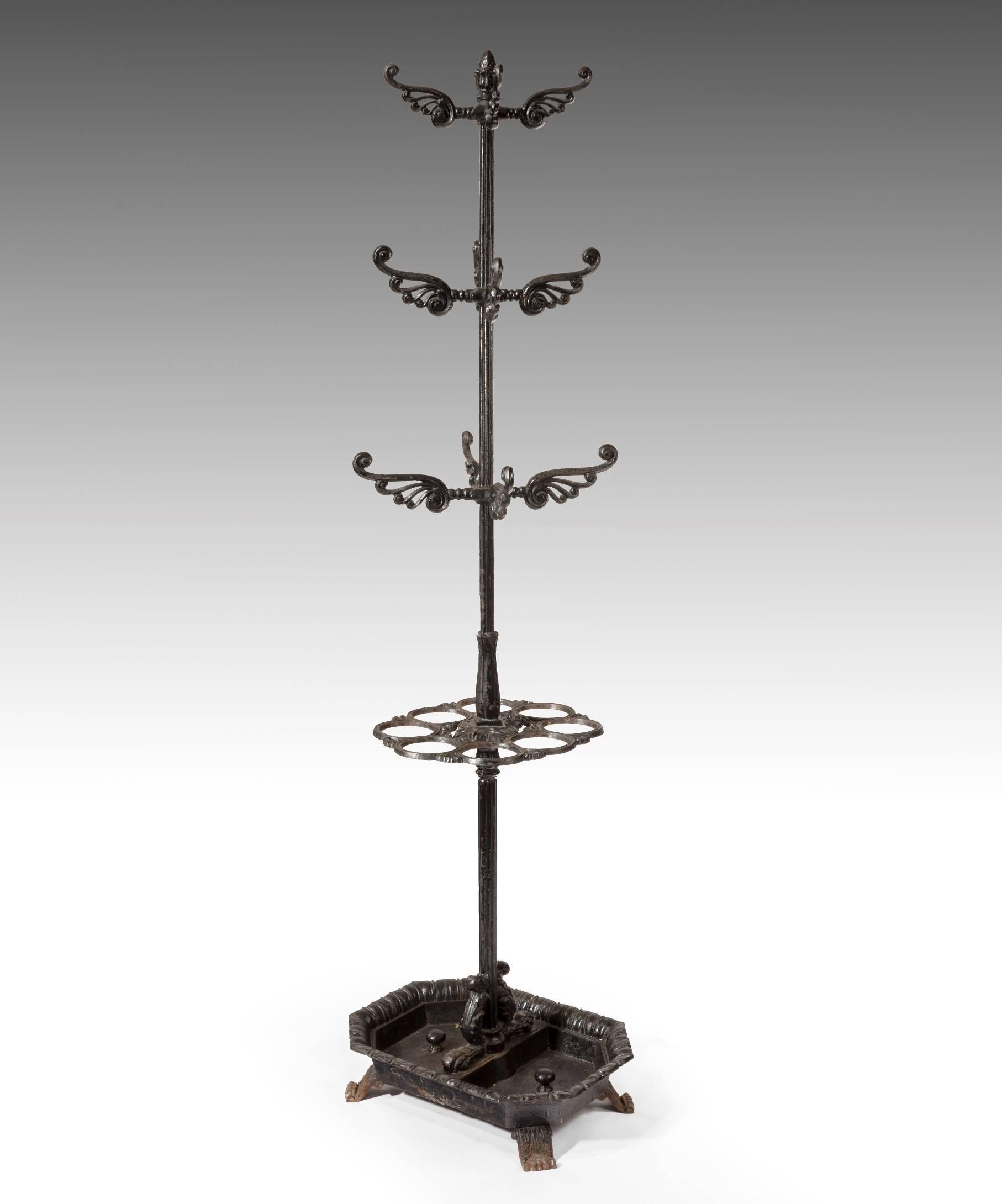 A handsome Victorian cast iron umbrella, coat and hat stand; the acorn finial above graduated scrolling arms and a ring for holding sticks and umbrellas with a drip tray below; raised on scrolling acanthus feet. This hall stand has been later