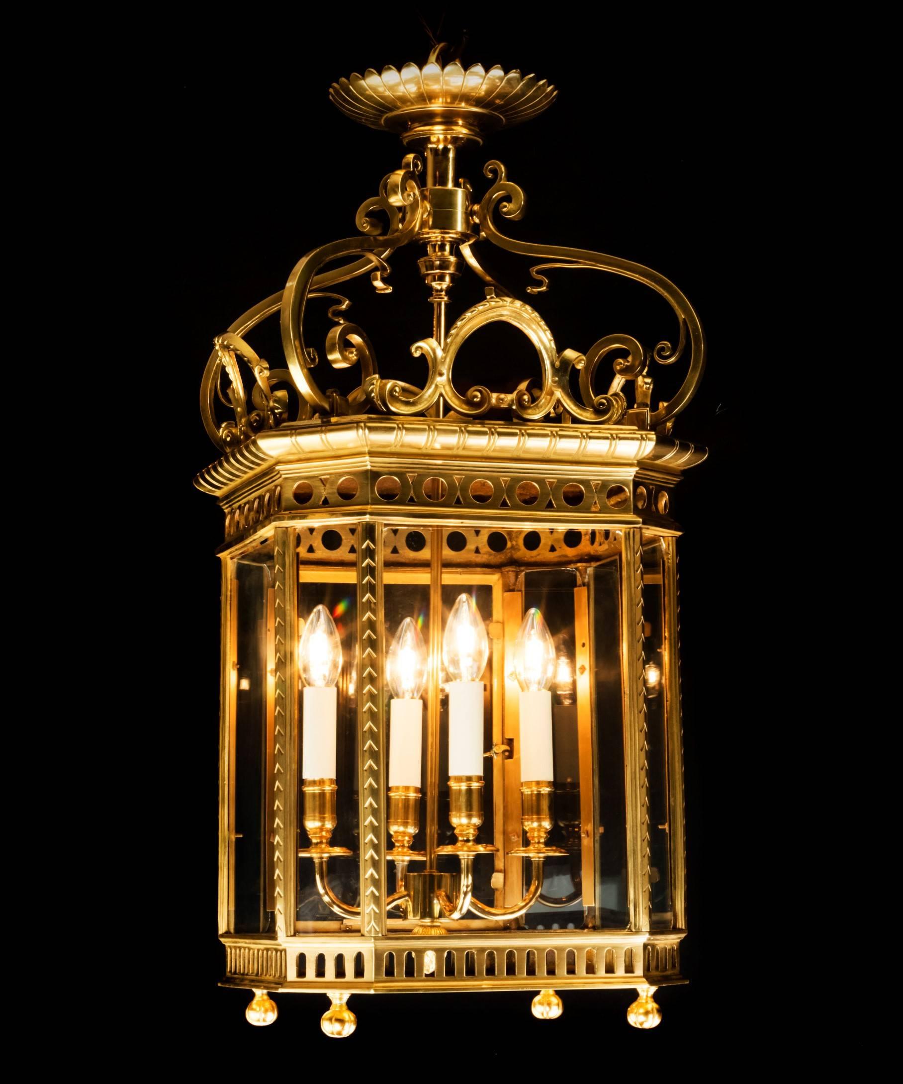 A large 19th century polished brass lantern; the basket top above four scrolling candle arms; the base with upturned finials. This lantern is larger than most examples having four candle arms and is perfect for a large hallway. The lantern has been