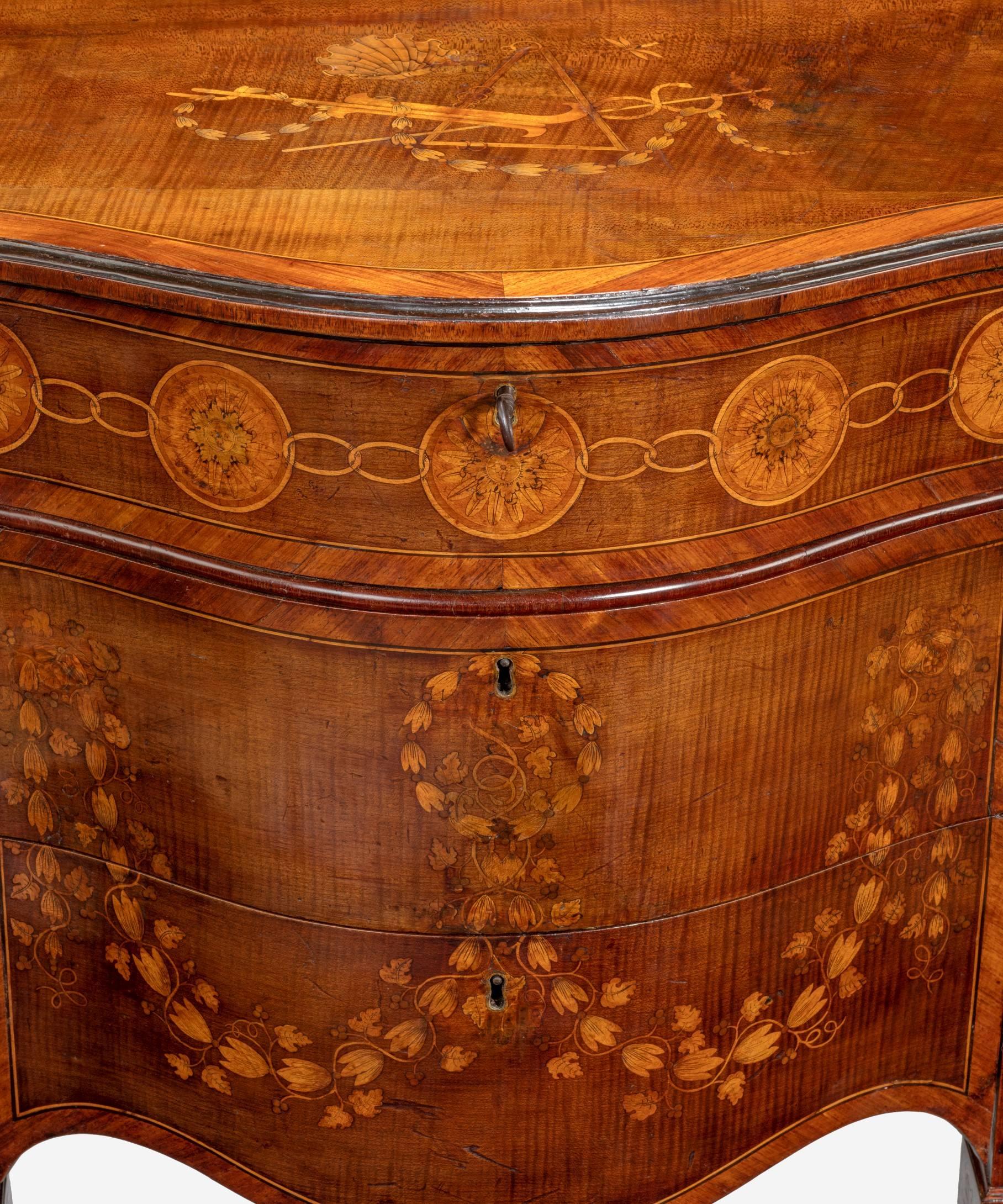An important George III sycamore and marquetry serpentine pier commode attributed to Mayhew and Ince; the top crossbanded in tulipwood and inlaid with a caduceus, a scallop shell, a triangle with rings, another instrument and a dragonfly above a