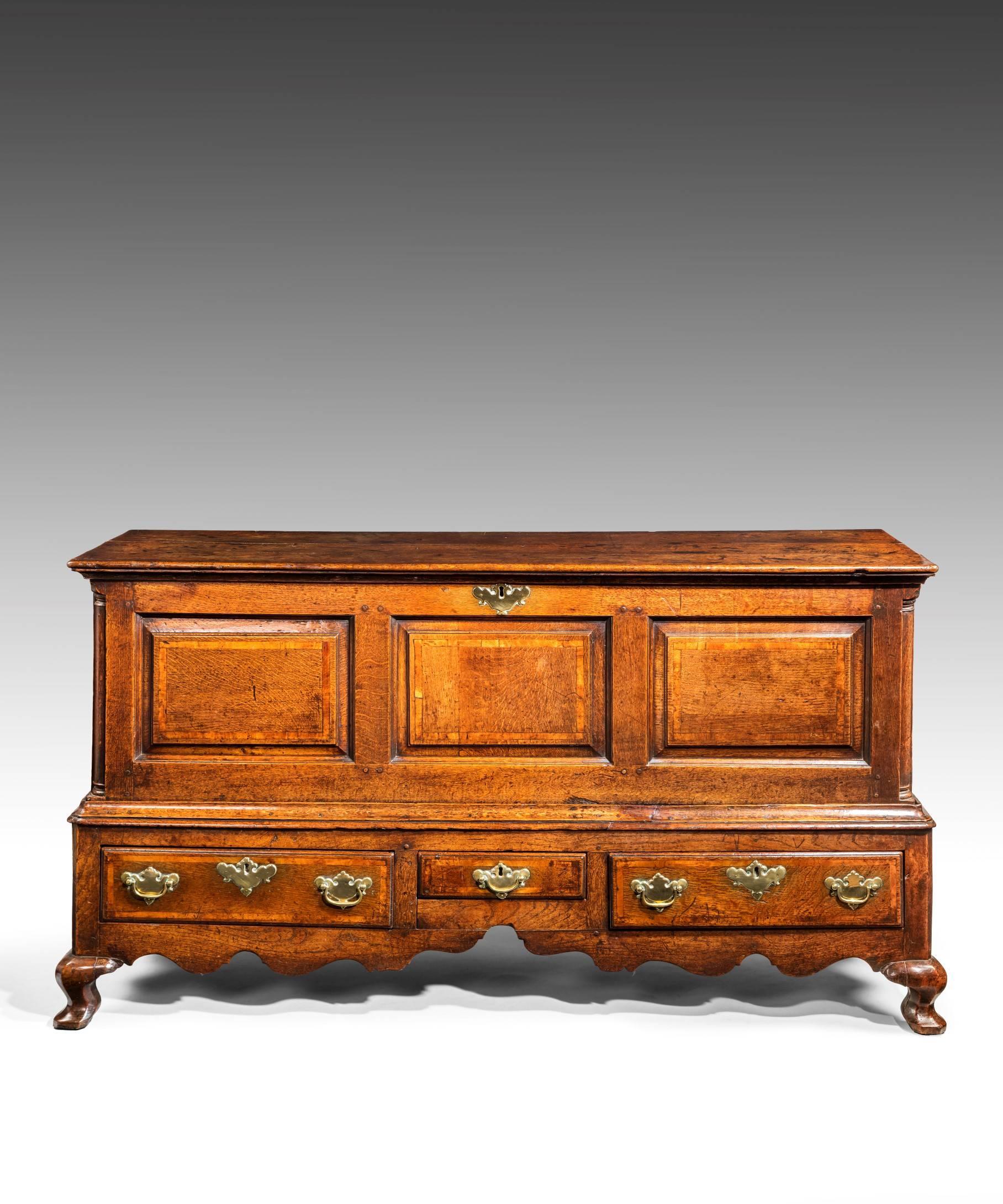 A rare George II period oak coffer/chest on stand; the lift-up lid above a fielded panel front crossbanded in walnut and with quarter columns inset into the corners; the stand with three drawers which have ovolo mouldings and are crossbanded in
