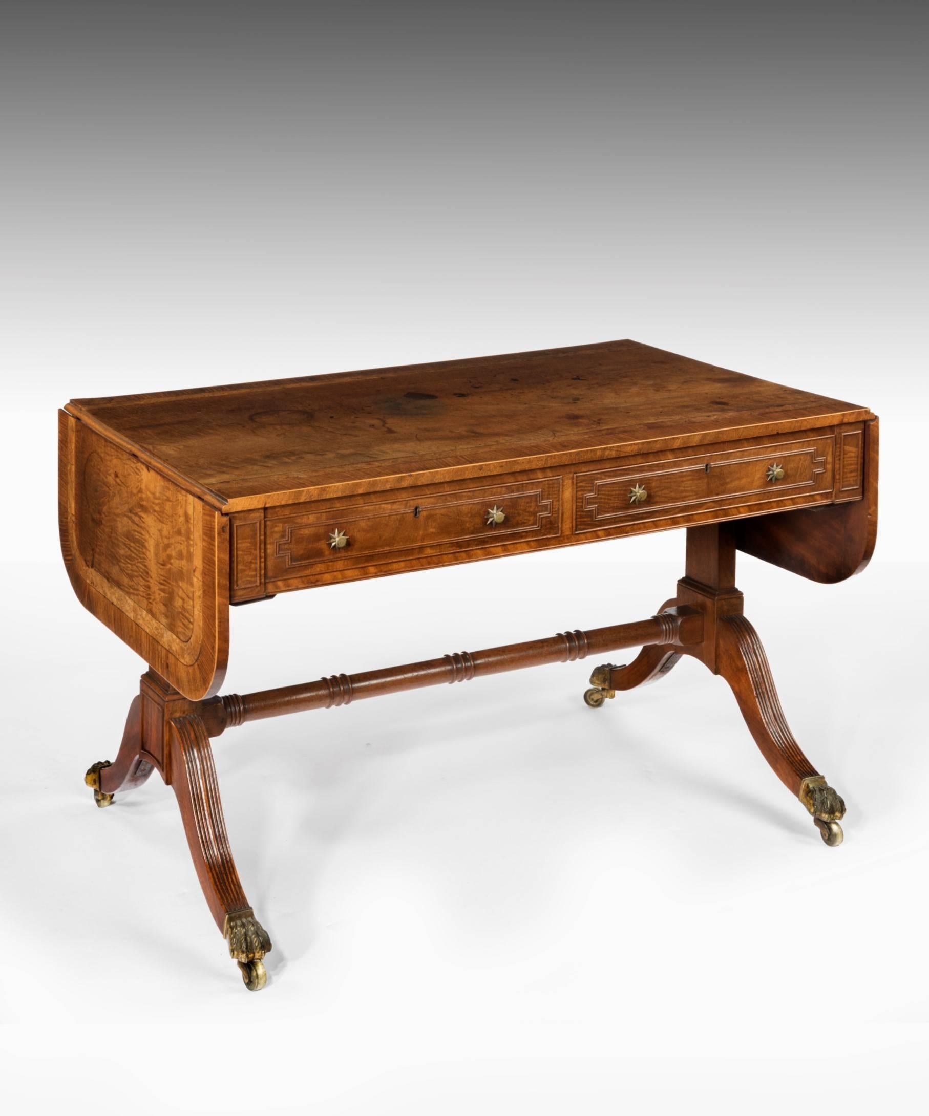 A beautifully patinated Regency period mahogany sofa table; the sofa table's well figured mahogany top crossbanded in bird's eye maple and rosewood above two frieze drawers which are decorated with a double cock bead moulding raised on end supports