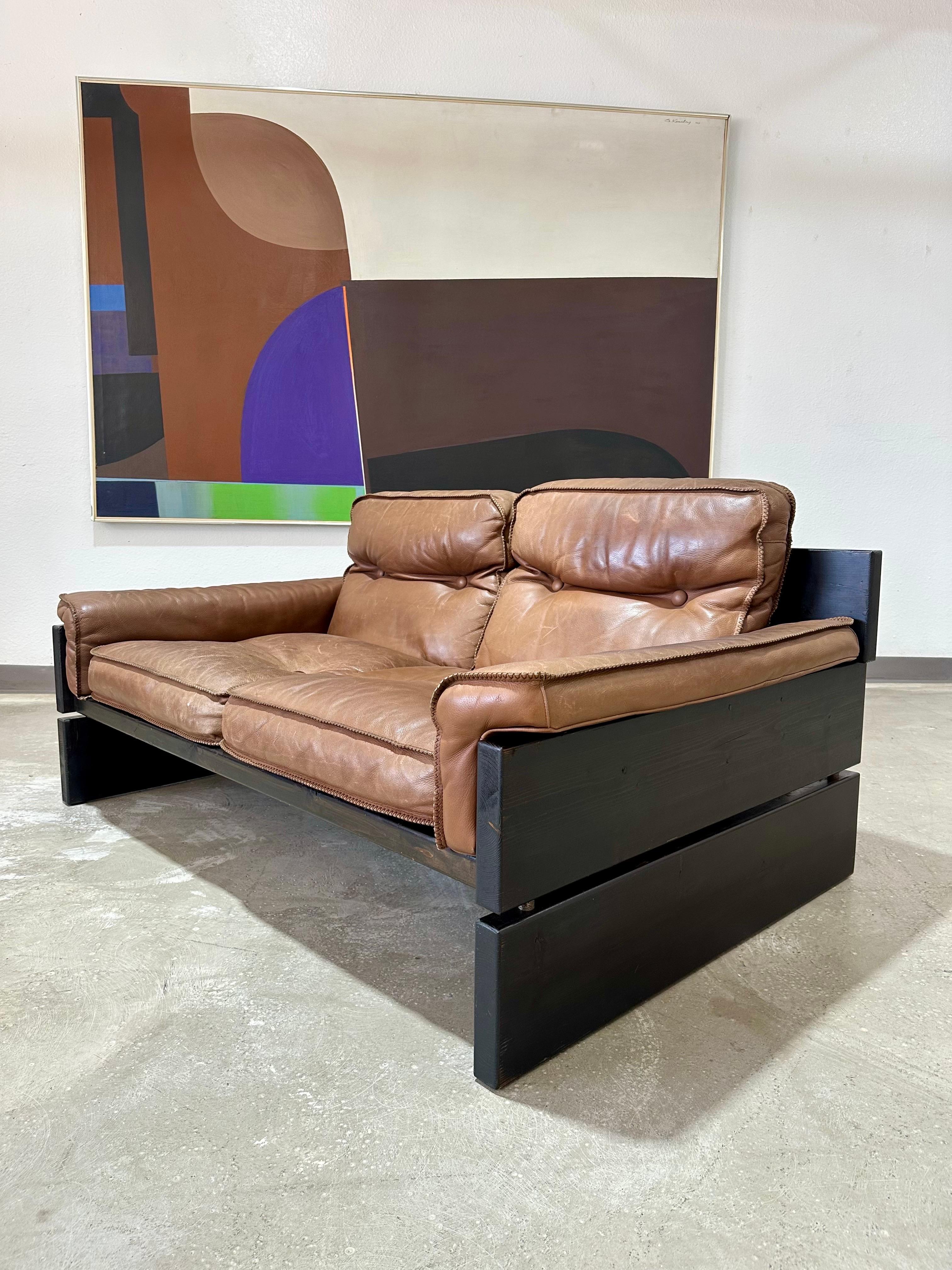 Vintage 1970’s Danish Brutalist Stained Pine and Brown Leather Sling Loveseat. Reminiscent of Brazilian Mid Century and Brutalist designs such as those by Percival Lafer. This unique and likely custom made low slung pine sofa is as beautiful as it