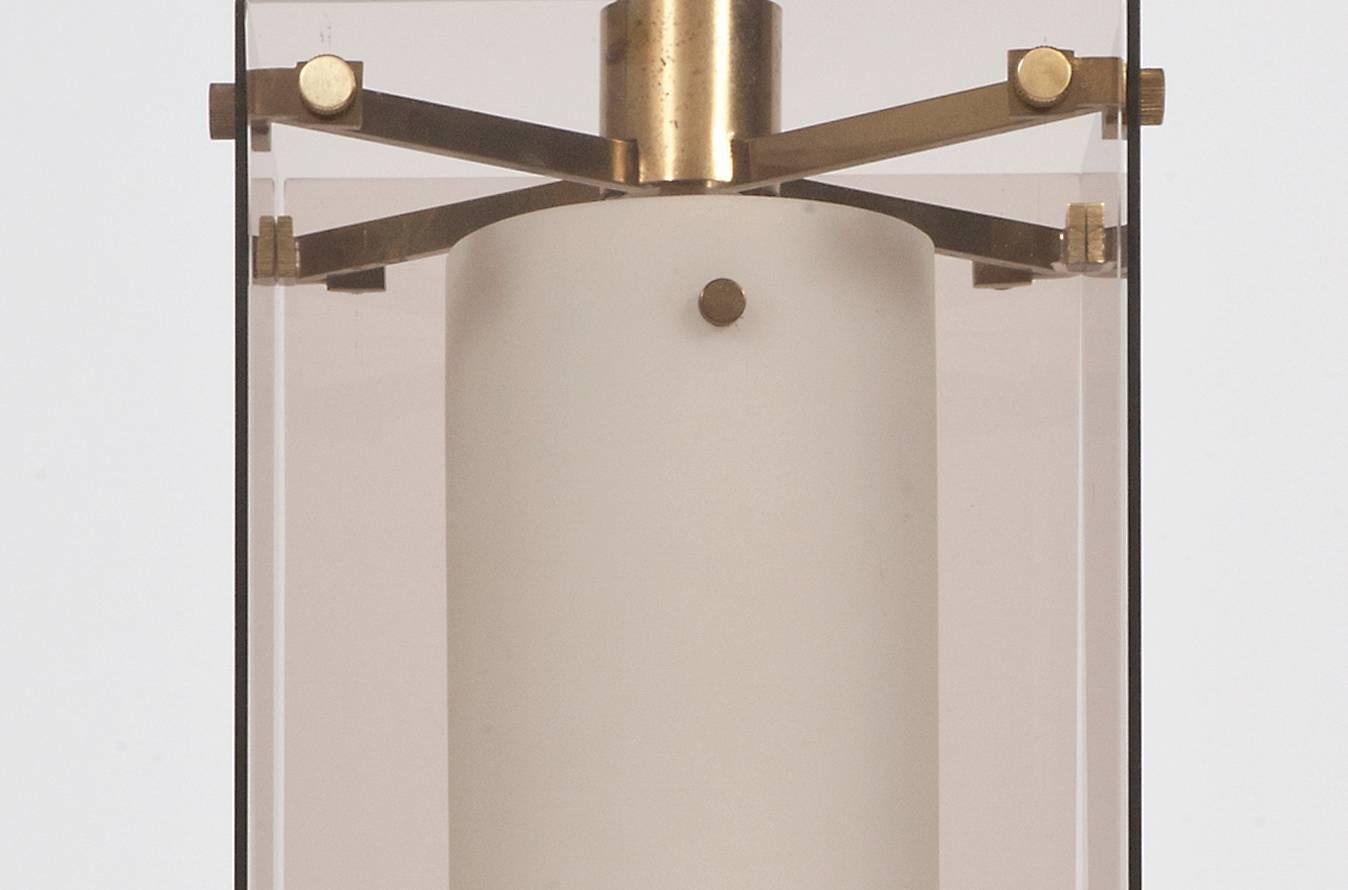 An opaline glass cylinder enclosed by four tinted clear glass plates set in a brass frame. Height of main glass elements 30 cm.