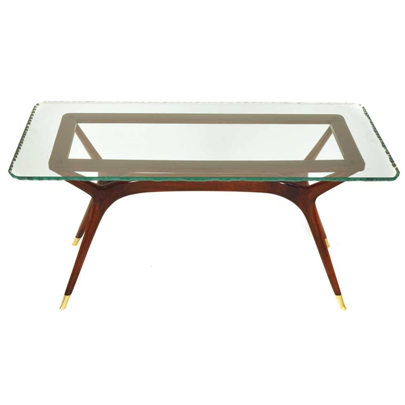 This piece was made in Italy in 1950s. Probably the design is from Ico Parisi. It is made of stained hardwood with a tabletop made of glass. The feet are covered with brass.