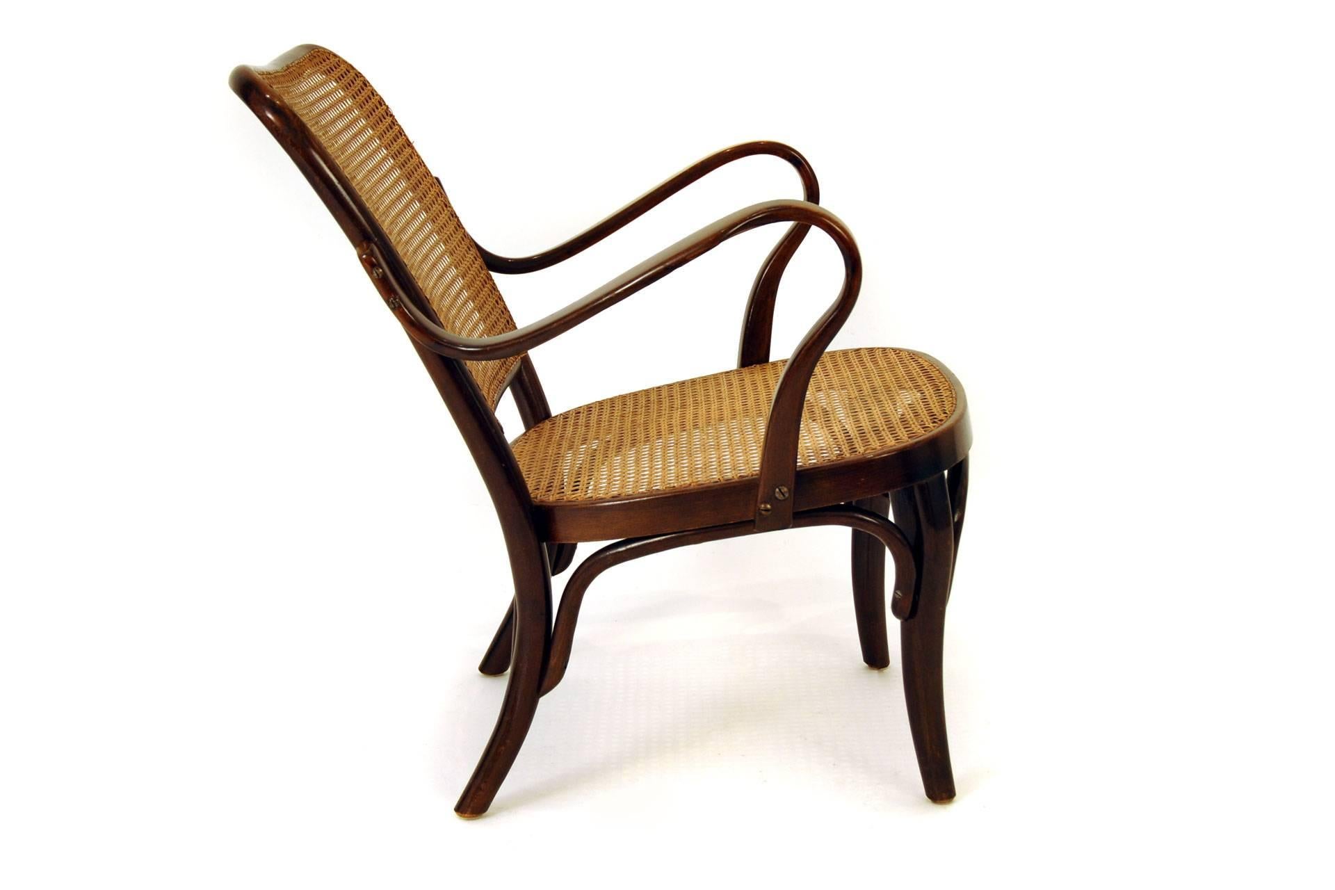 The armchair was designed by Josef Frank in 1930s The model name is Kaminfauteuil A. 752. It was manufactured by Thonet. The furniture frame is made of bent beech which is stained. The network is probably renewed and in very good condition. There