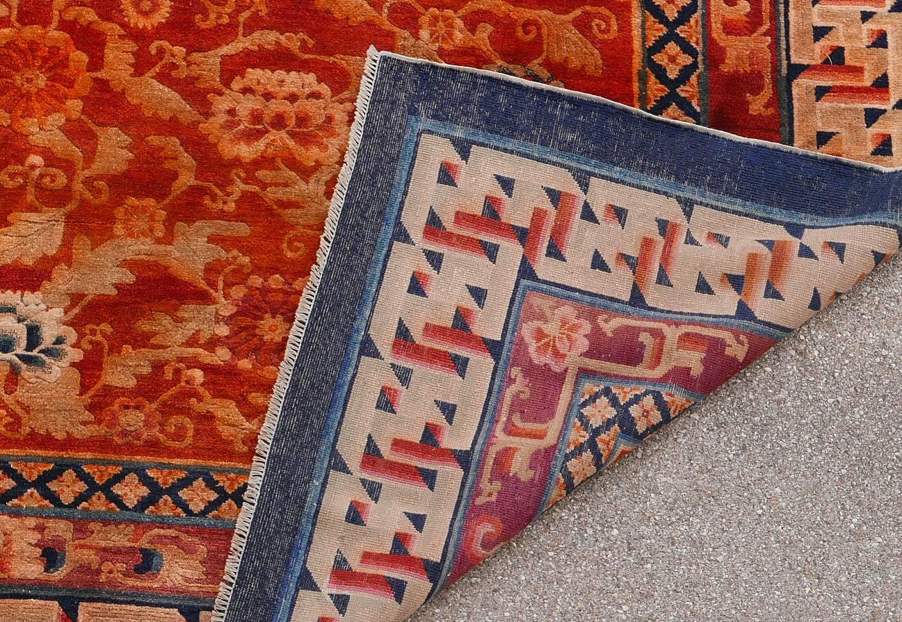 This antique Baotou temple rug is a stunning example of rugs made specifically for temples and monasteries.
The warm red-brown central field is decorated with flowers and foliage with three blue flowers standing out in particular.
The field is