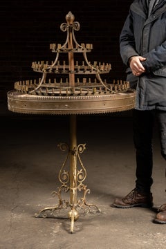 Mesa con candelabro antiguo de latón de varios niveles sobre un soporte ornamentado