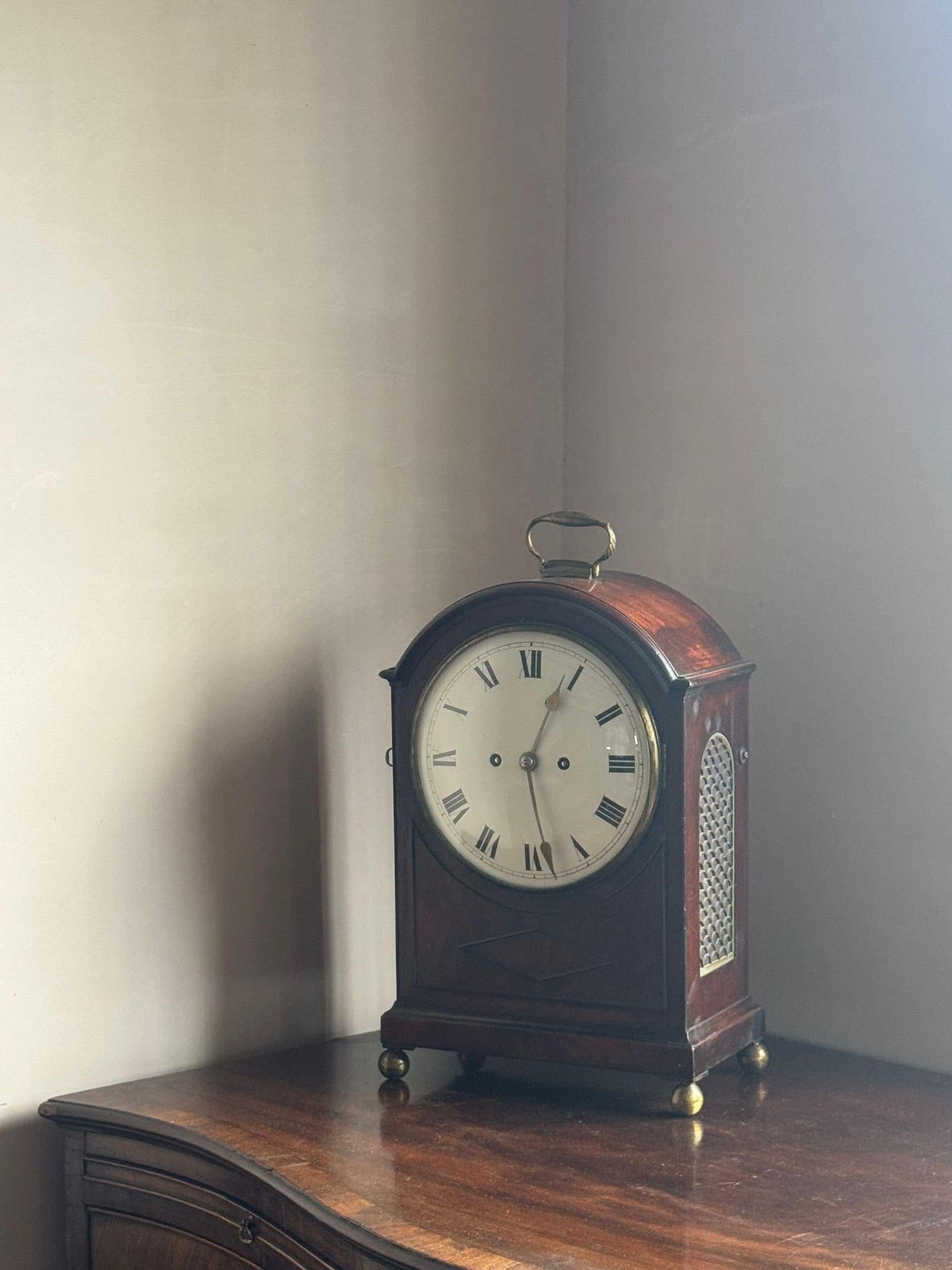 Orologio da tavolo a mensola degli inizi del XIX secolo con movimento a doppia spoletta di 8 giorni. La cassa ad arco in mogano con modanature applicate è di un bel colore intenso ed è in ottime condizioni originali. Dimensioni: H 47cm L 27cm P 17cm