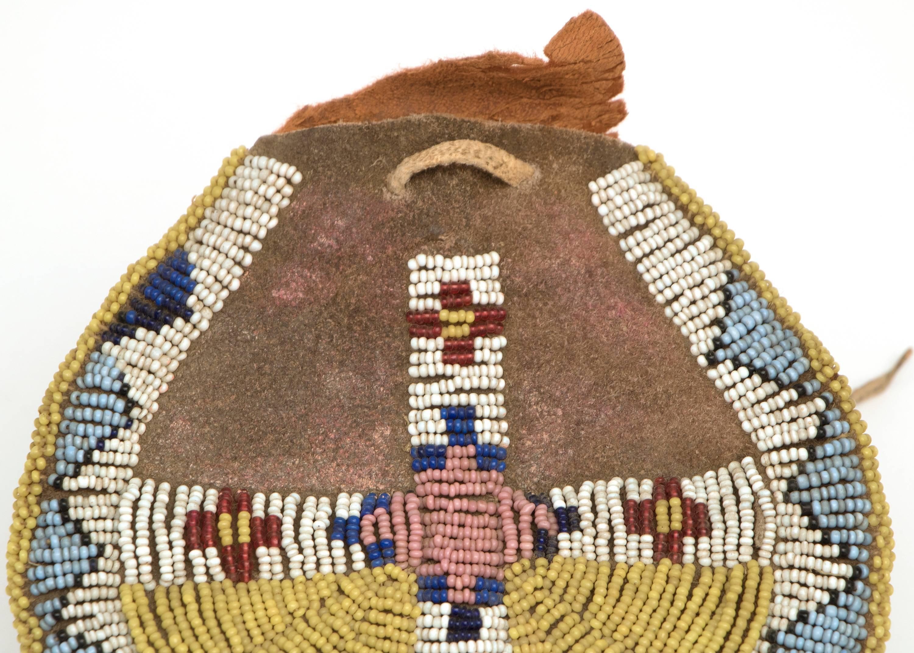 Constructed of native tanned hide and beaded in geometric patterns with stylized tepee and cross motifs in yellow, white, blue and red glass trade beads.

The Arapaho, members of the Plains Indian culture group, were nomadic with territory