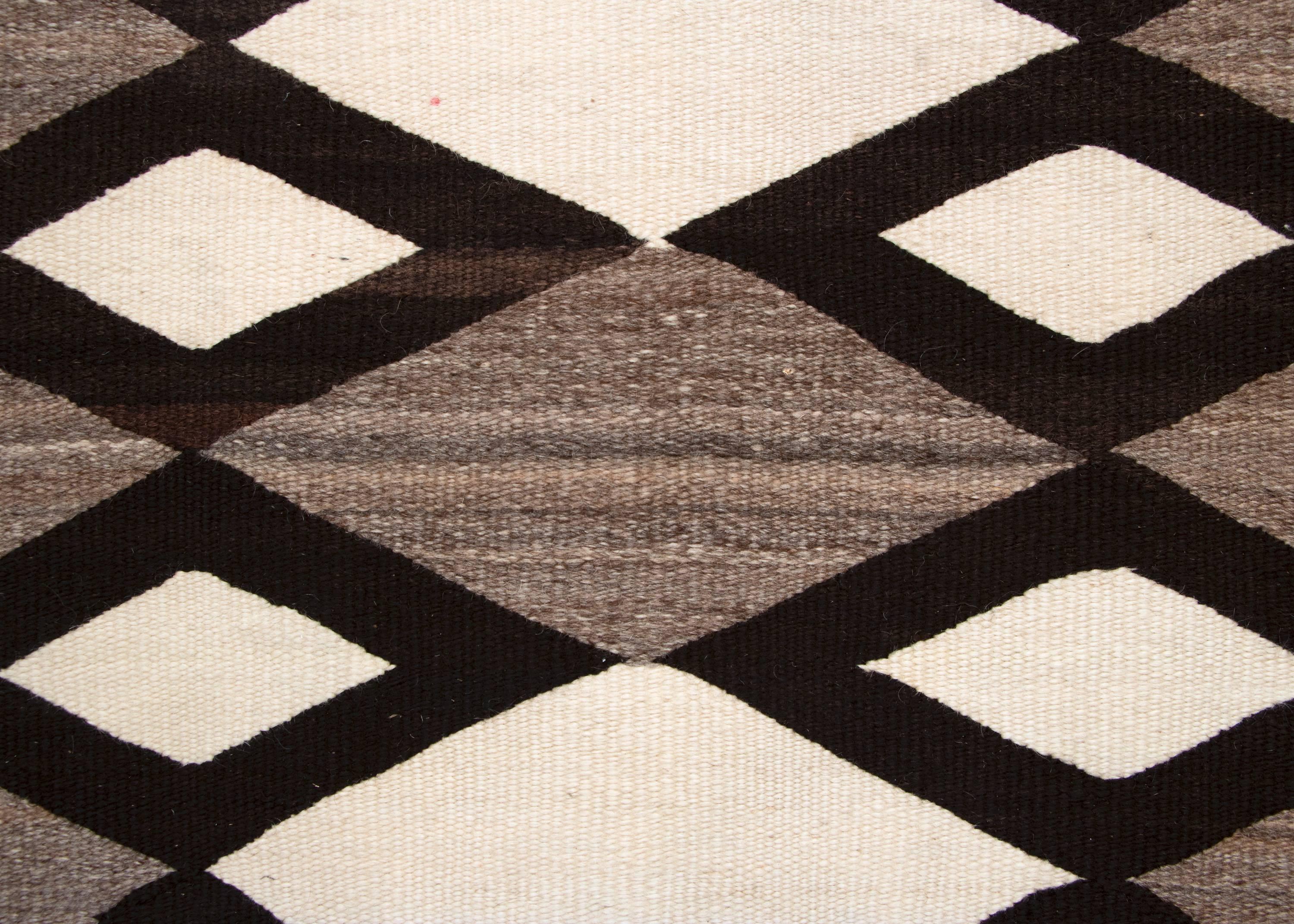 A regional/Pan Reservation rug woven of native hand spun wool with a striking diamond pattern in natural fleece colors of ivory/white, black/brown and gray with subtle brown variations throughout.  Likely woven in the late 19th or very early 20th