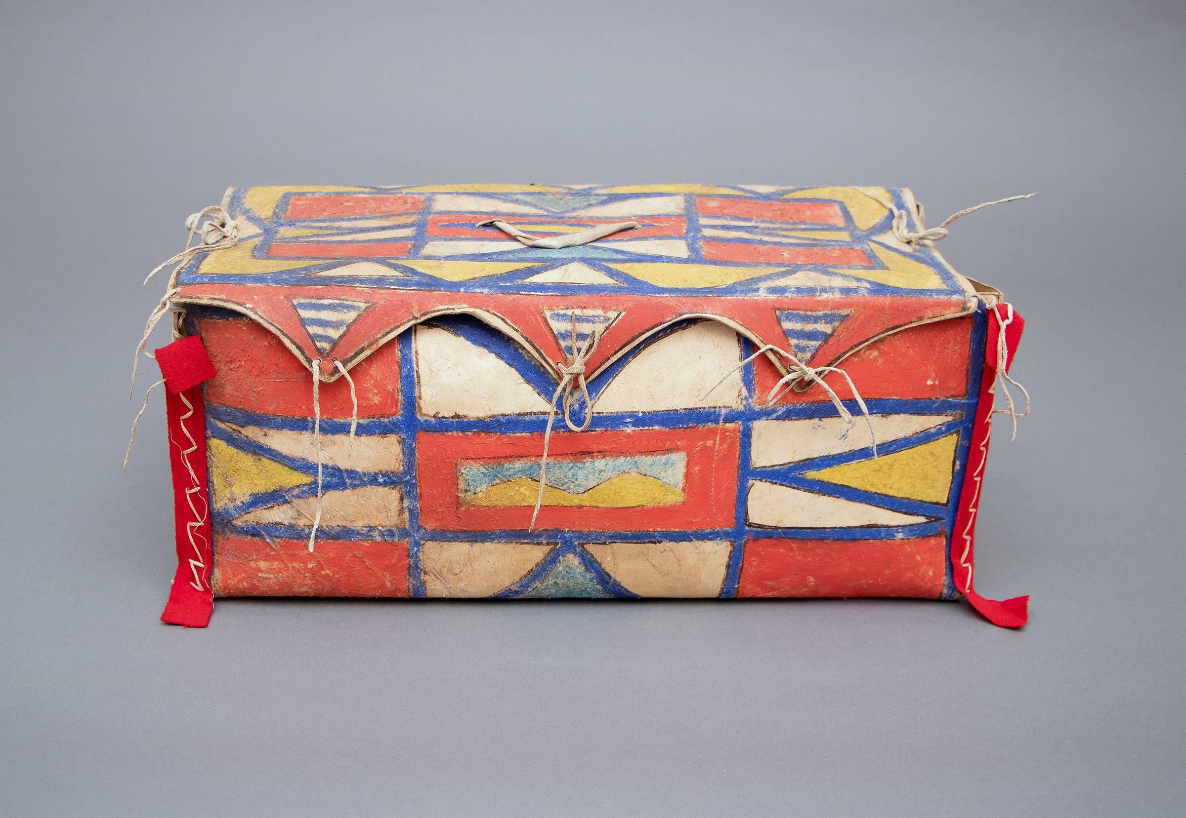 A rare box form constructed of rawhide and intricately painted in an abstract design with natural pigments and red trade cloth.
This was created by a North American Indian living in the Plateau cultural area - encompassing portions of what is now