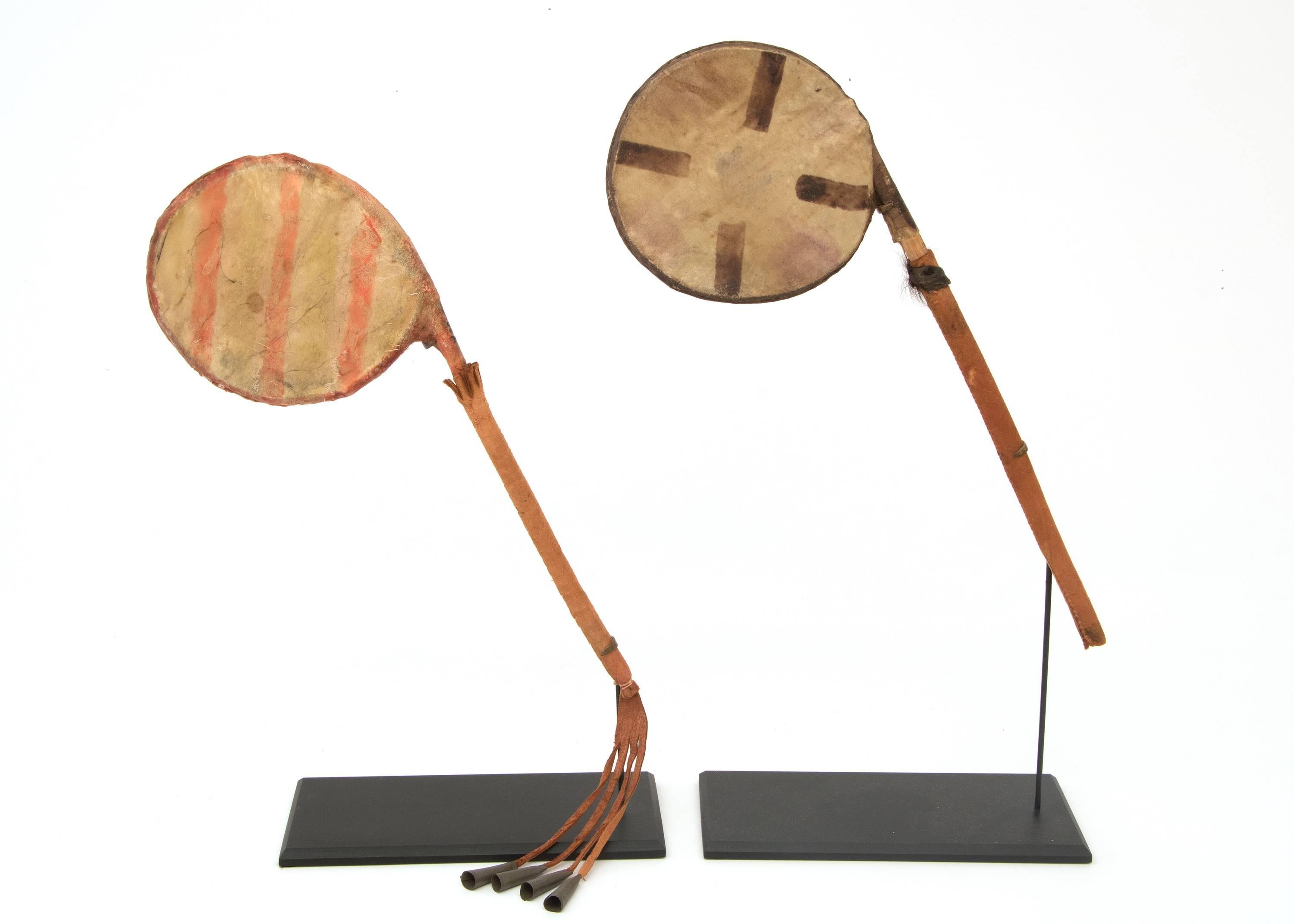 A remarkable pair of rattles constructed of hide with wood and painted with traditional plains designs.

Overall dimensions of both works as shown in the primary image are 16.75 (height) x 17.25 (width) x 3.75 (depth).

Individual measurements