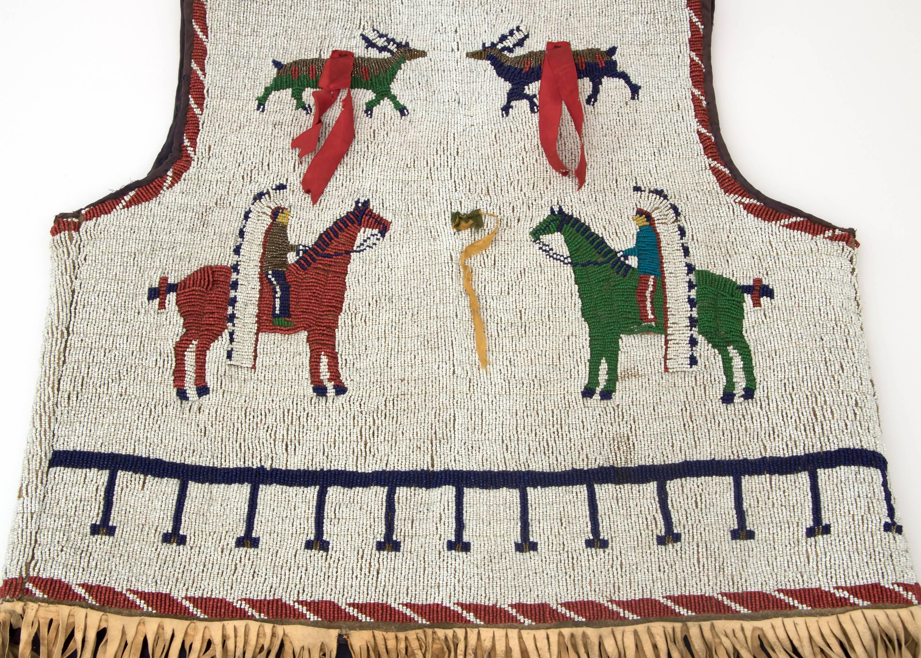 Pictorial plains/American Indian vest fully beaded and fringed. Depicting natives on horseback with feather headdresses and elk/deer.

Constructed of Native tanned hide with glass trade beads, cloth and ribbon. Created at the end of the 19th or
