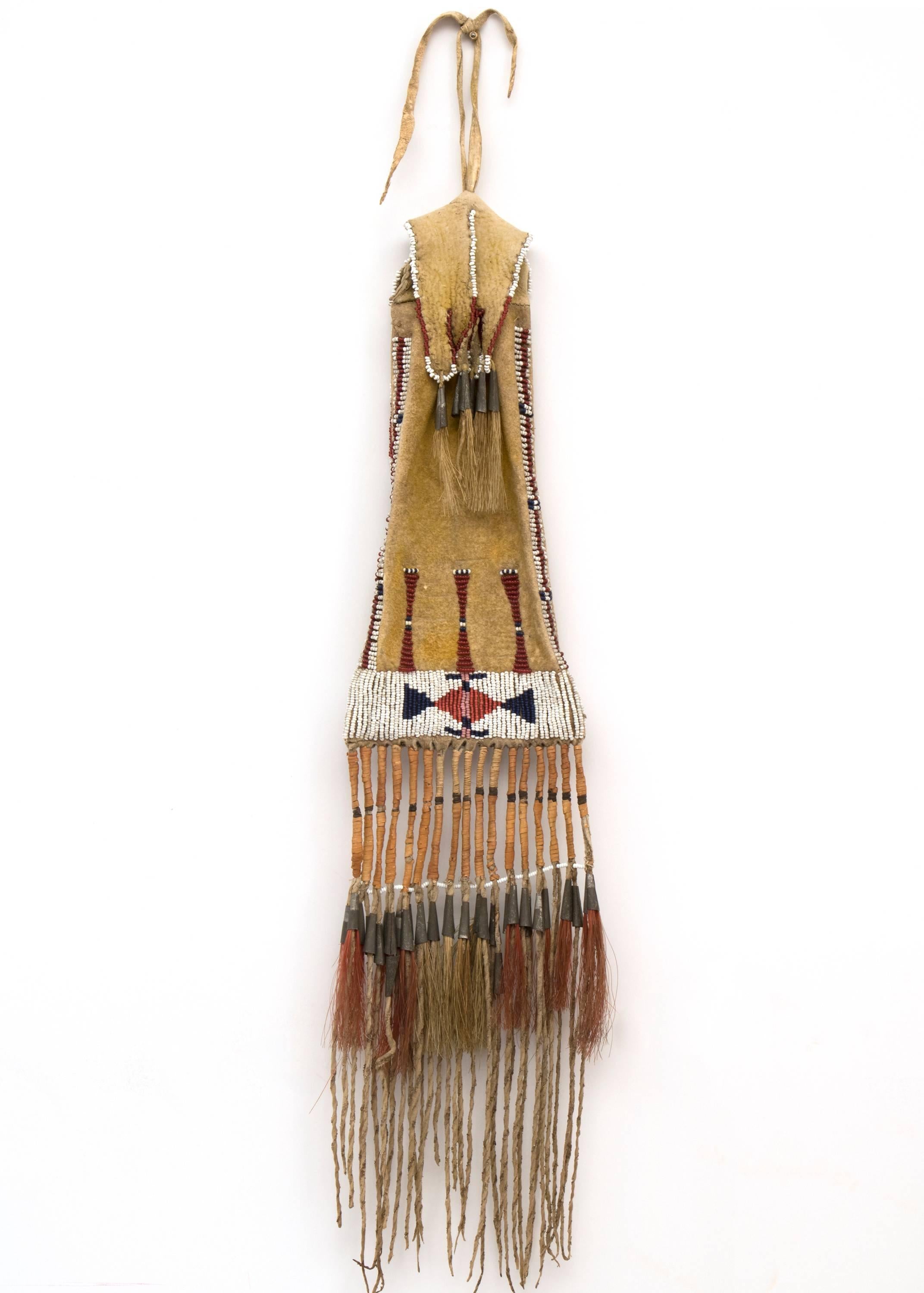A late Classic period women's Southern Arapaho tobacco bag. Constructed of native tanned hide with glass trade beads, horse hair and tin-cone tinklers.

Provenance:
Peter Gruber (Mandalay Entertainment)
Private Collection, Aspen.

Expedited