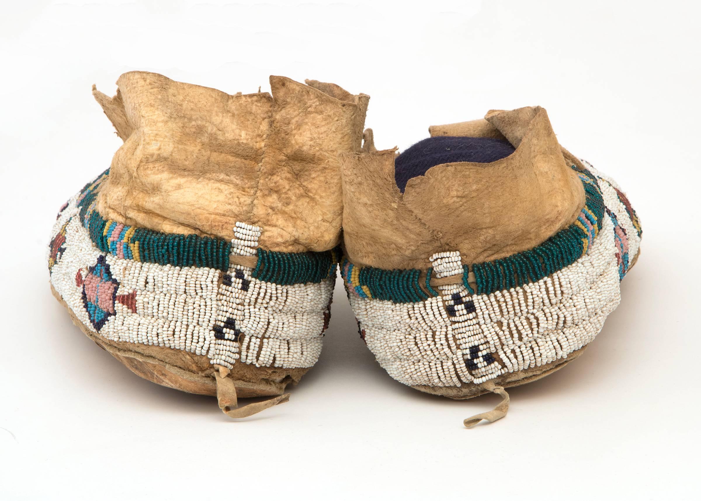 Pictorial beaded moccasins constructed of native tanned hide with glass trade beads. Design elements include stylized buffalo tracks, geometric elements and avian/humanoid figures.

Expedited and International shipping is available, please contact