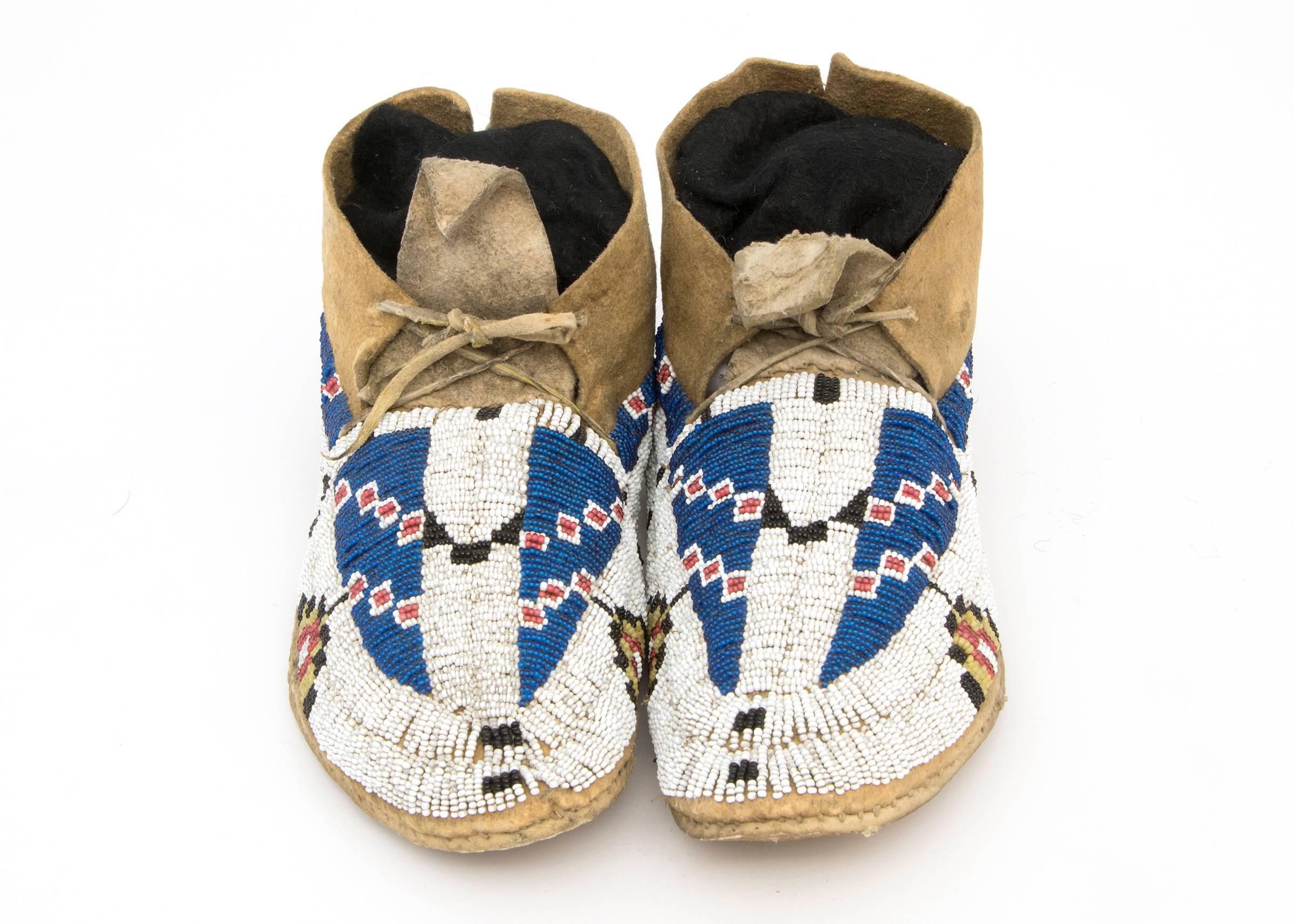 Created for a child, this pair of moccasins was constructed from native tanned hide. Fully beaded uppers with 