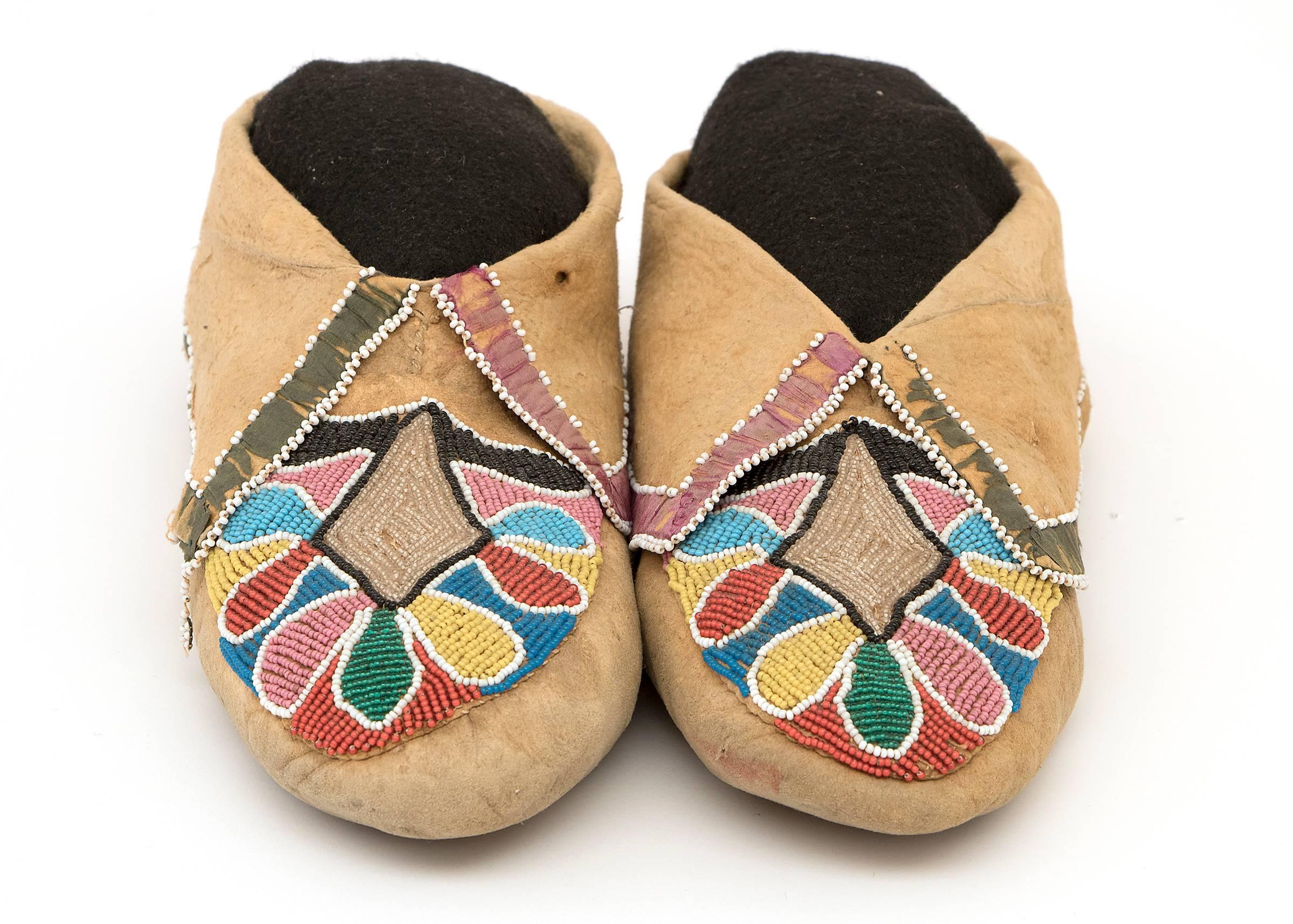 A rare early pair of Classic Period (Pre-Reservation era) soft-soled moccasins. Constructed of native tanned hide and exquisitely beaded with trade beads. The cuffs are adorned in ribbon with edge-beading.

Provenance:
Lessard Collection - SD