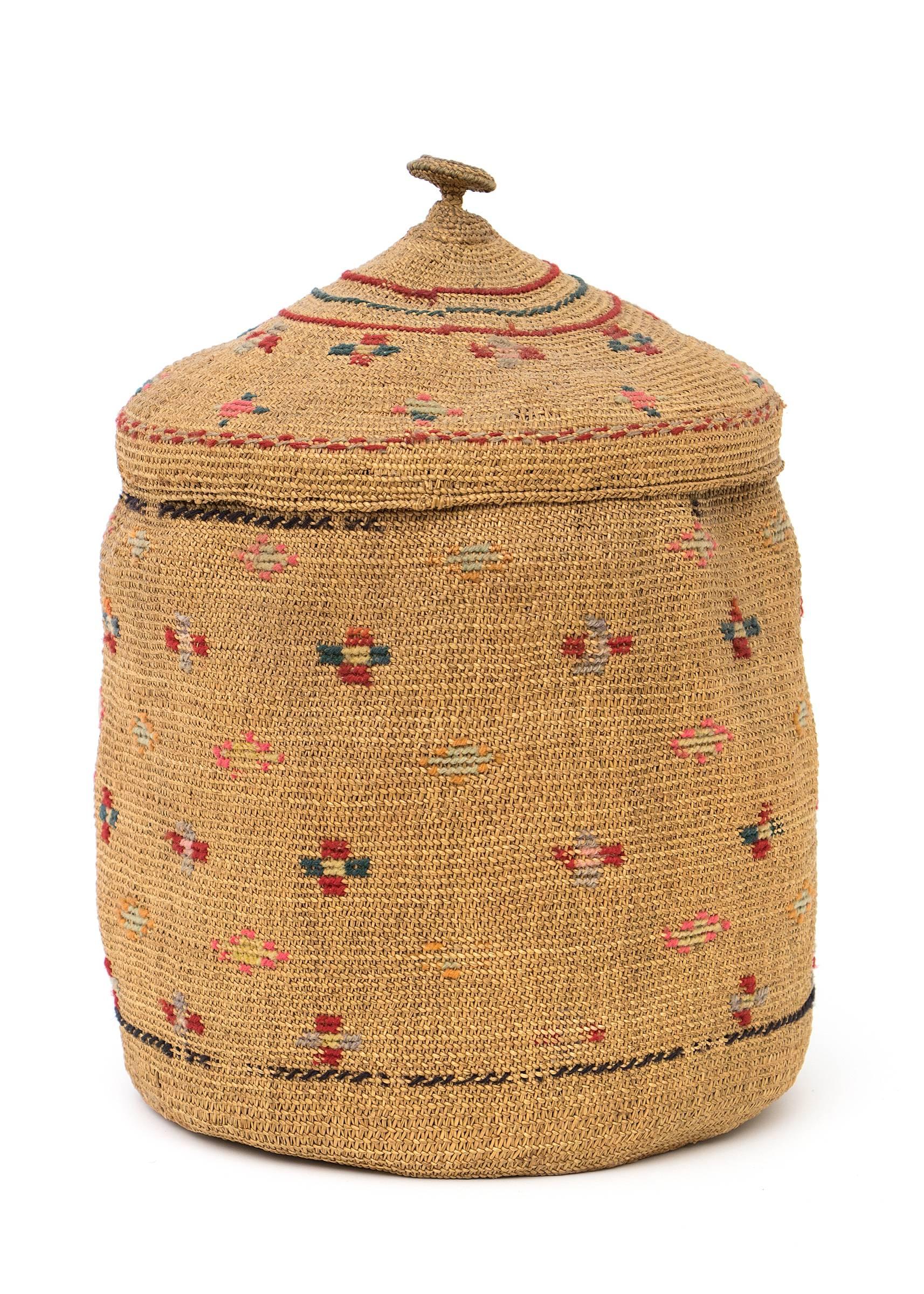 A lidded basket very finely woven of native grasses incorporating geometric designs including crosses of red, gray, green and yellow yarns.

The Tlingit peoples are indigenous to the Pacific Northwest Coast; inhabiting southeastern Alaska,