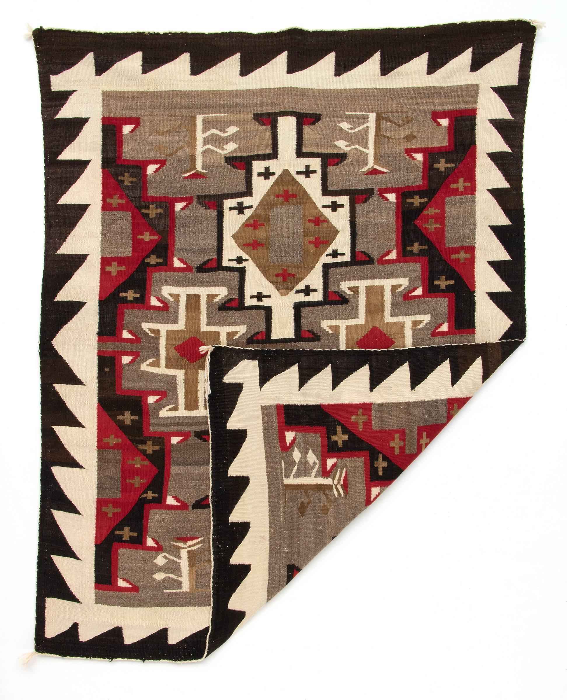 Woven of native hand-spun wool in natural fleece colors of ivory, black/brown, grey and camel with aniline-dyed red. Pictorial elements include cross and plant motifs.

This textile is well suited for use on the floor as an area rug or as a wall