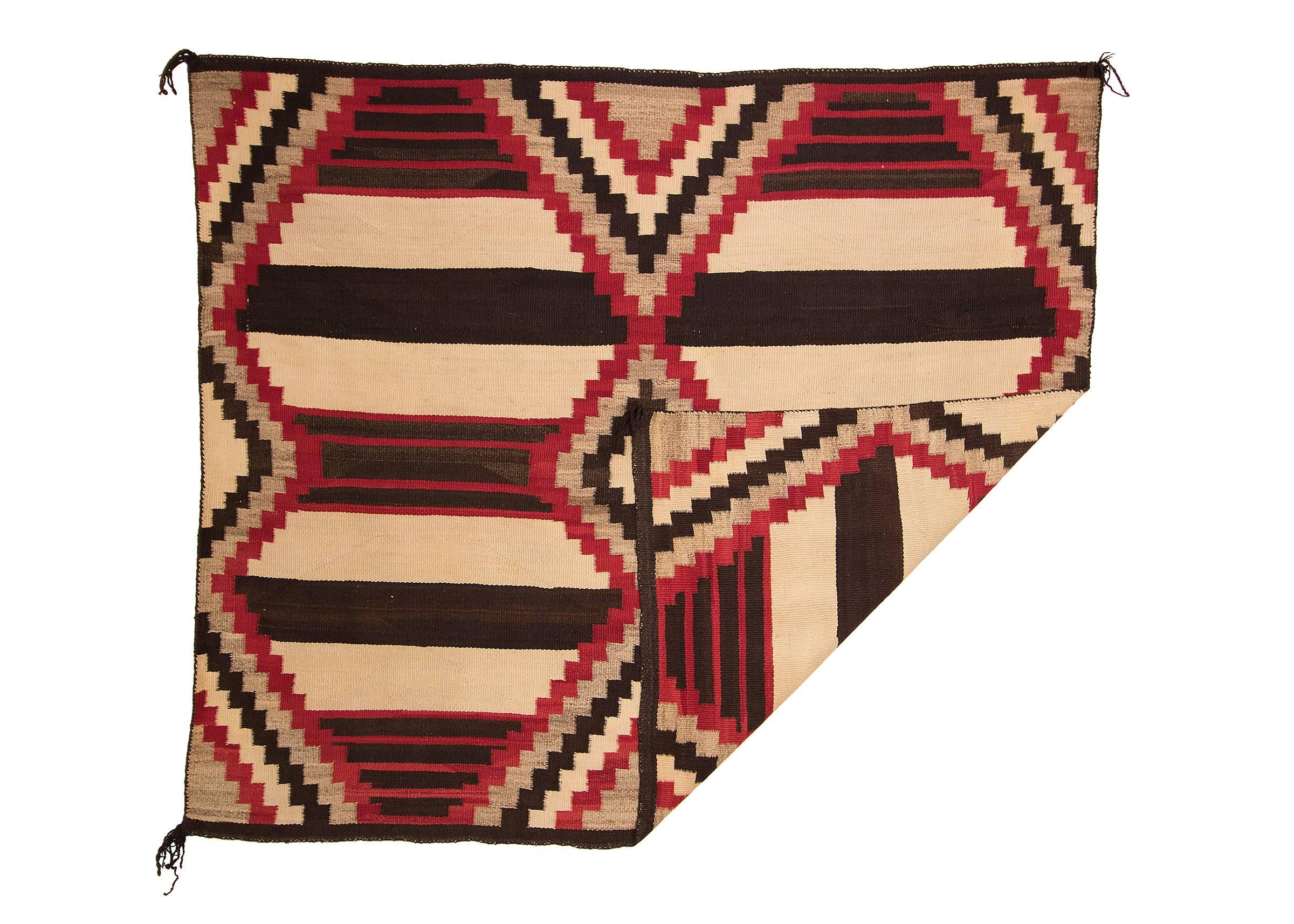 A Navajo chiefs blanket in a fourth phase/variant pattern. Woven of native hand-spun wool in natural ivory, dark brown and grey fleece with aniline dyed red in a variant of the nine-point chief's pattern against a Classic banded ground.

This