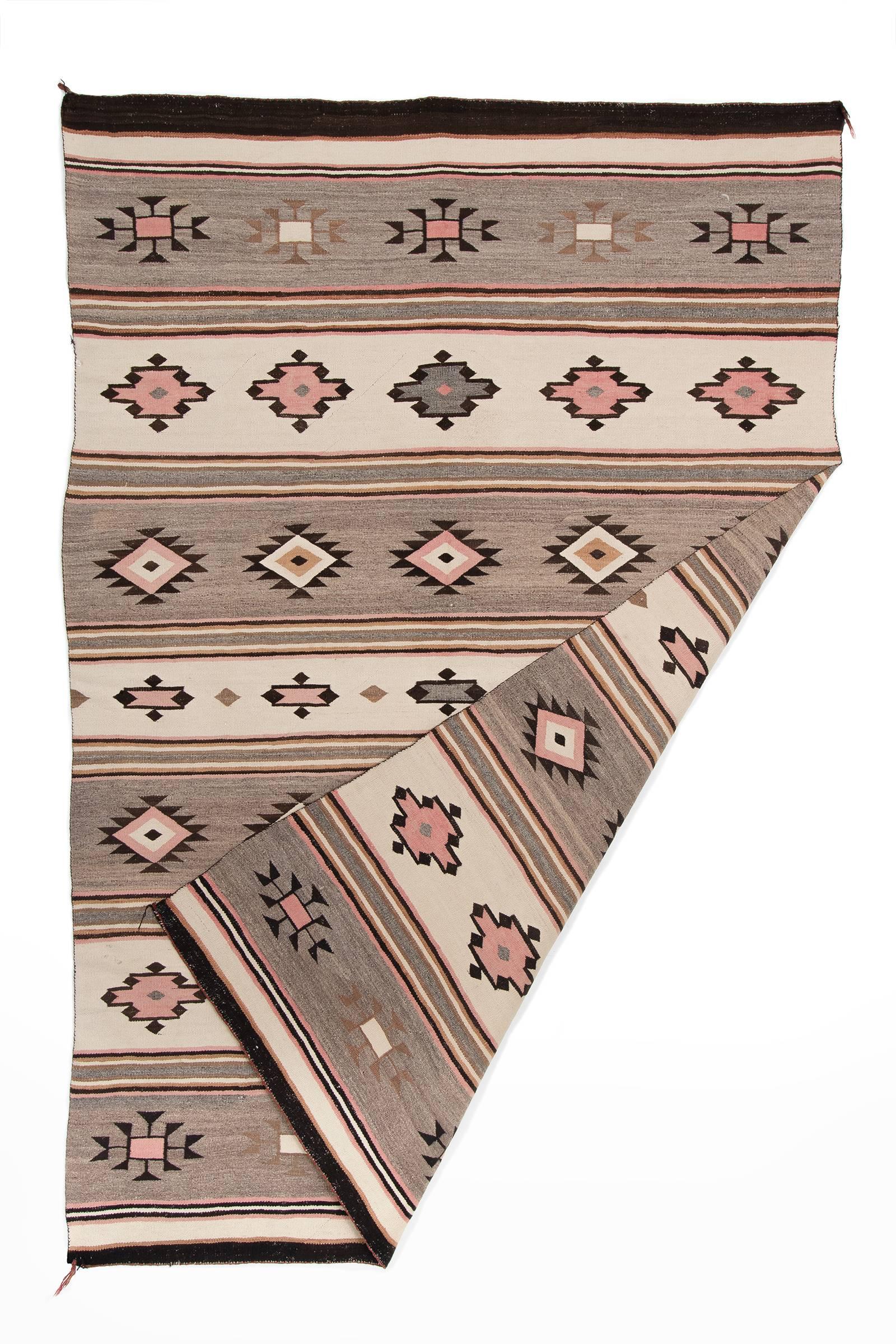 A vintage Navajo rug woven of native hand-spun wool in a Chinle Revival pattern. This style of Regional Rug began in the 1920s at Chinle, Arizona. A classic banded Chinle design with diamonds in natural grey, ivory and brown fleece with aniline-dyed