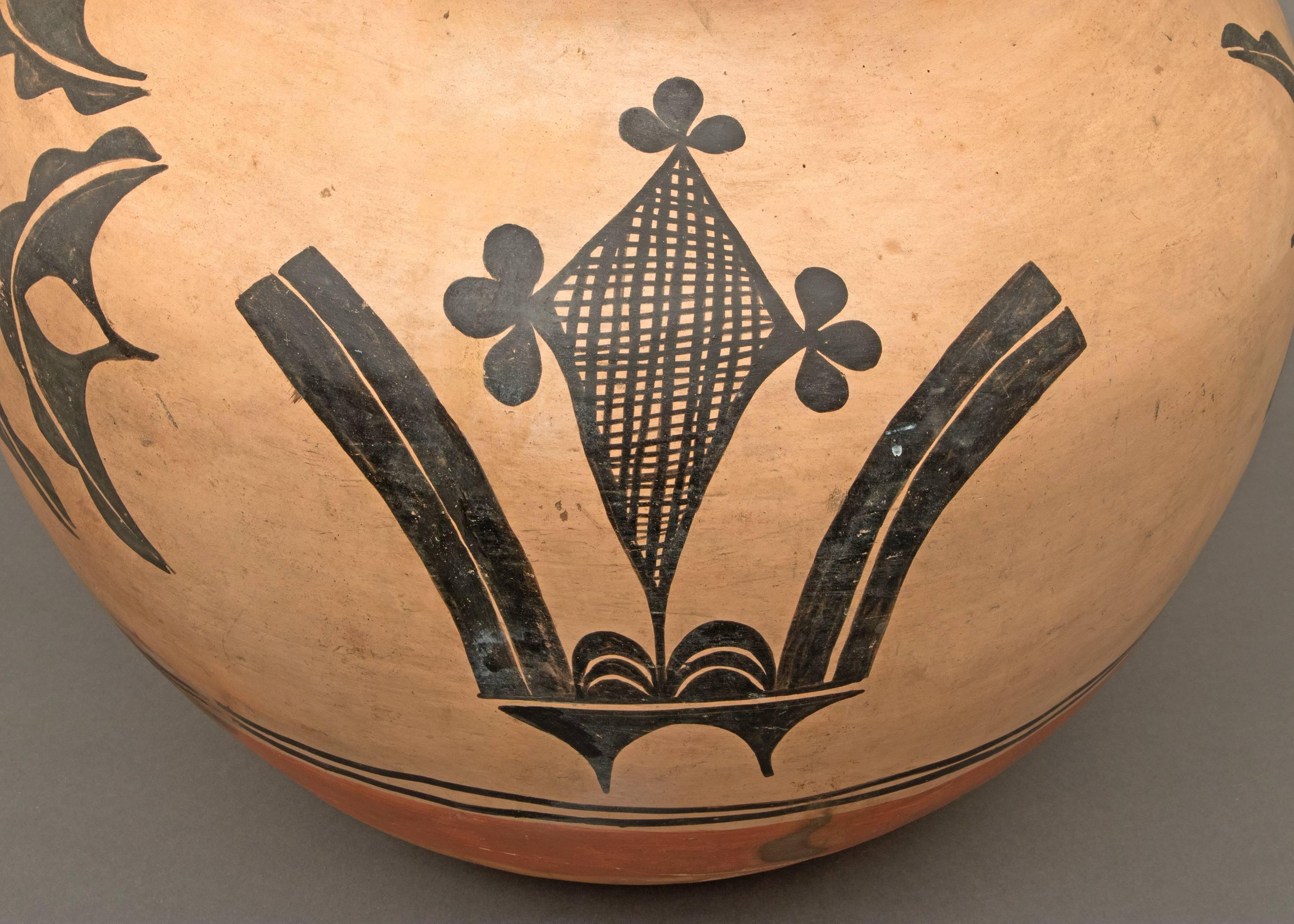 This large antique Native American Southwestern polychrome storage jar/olla has a graceful form and is painted in slip glazes in geometric and foliate designs. Created by a potter at Santa Domingo Pueblo during the late 19th or early 20th