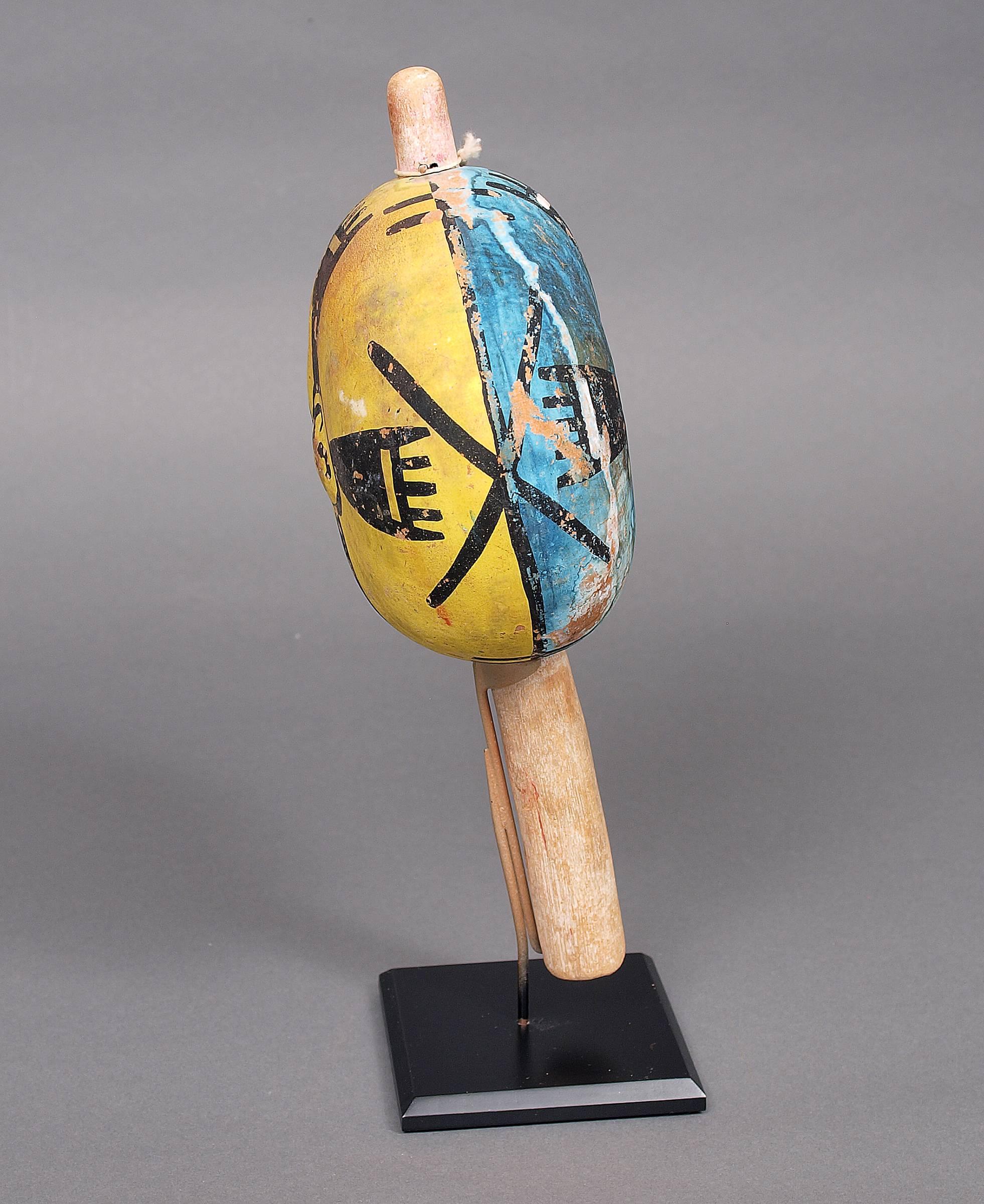 A traditional gourd rattle with blue, yellow and black vegetal paints and a wooden handle. Created by a member of the Hopi (Pueblo) tribe during the late 19th or early 20th century in Northern Arizona.

Custom display stand is