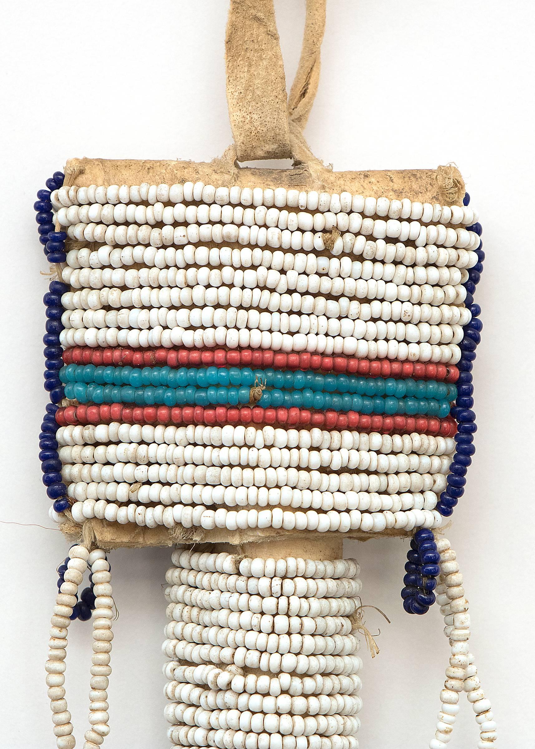 Antique 19th century Native American Sioux (Plains Indian) beadwork woman's awl case constructed of native tanned hide, sinew-sewn with trade beads in white, dark blue, Pony-Trader blue and white-heart red with tin cone tinklers. Cases like this