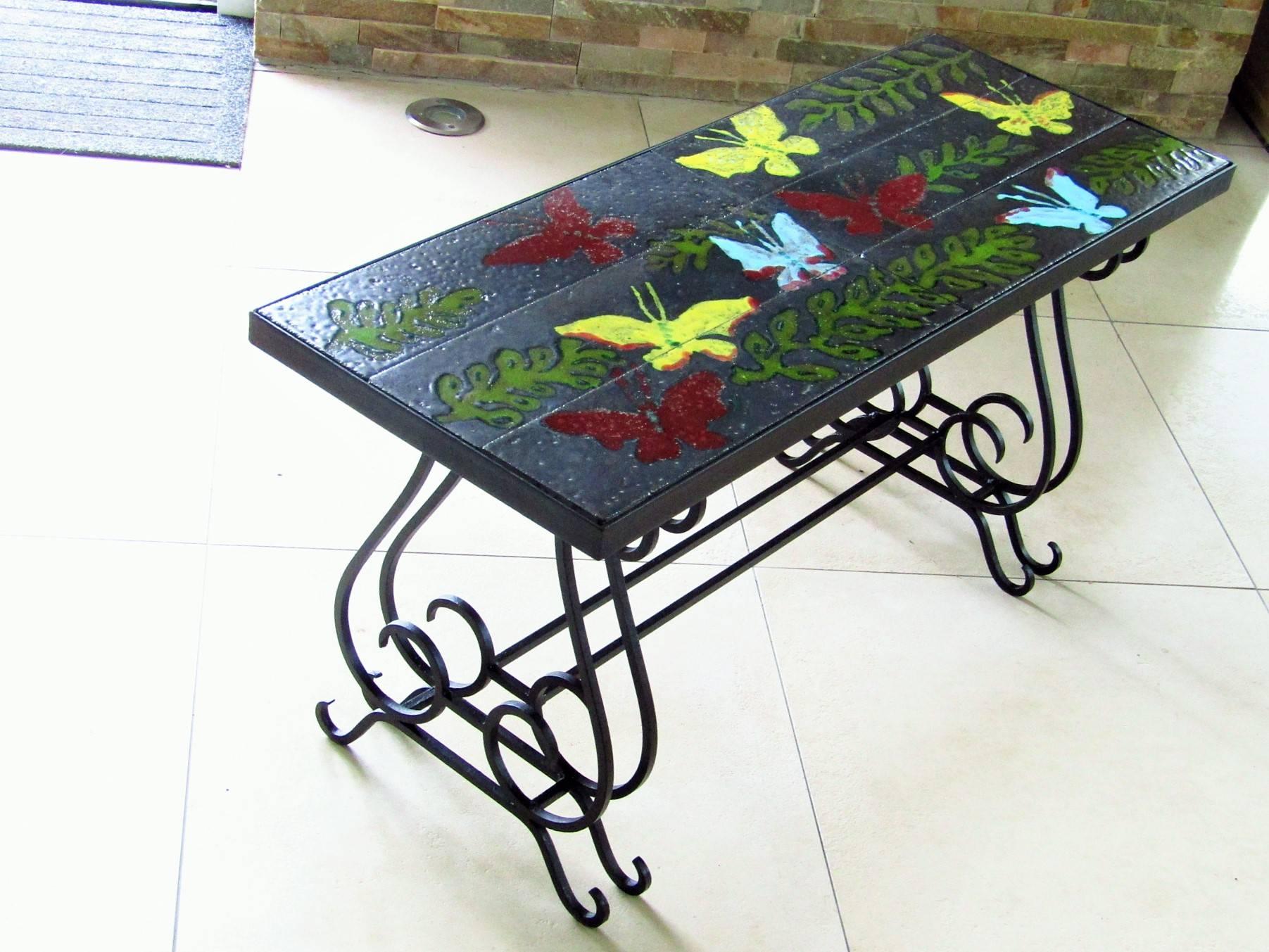 Mid-Century coffee table with lavastone tiles from Vallauris. Hand-painted and enameled Decor. Base solid wrought iron, France, circa 1940.

Jacques Adnet used the same tiles (see google: table - adnet) for his work. These tiles are a very early