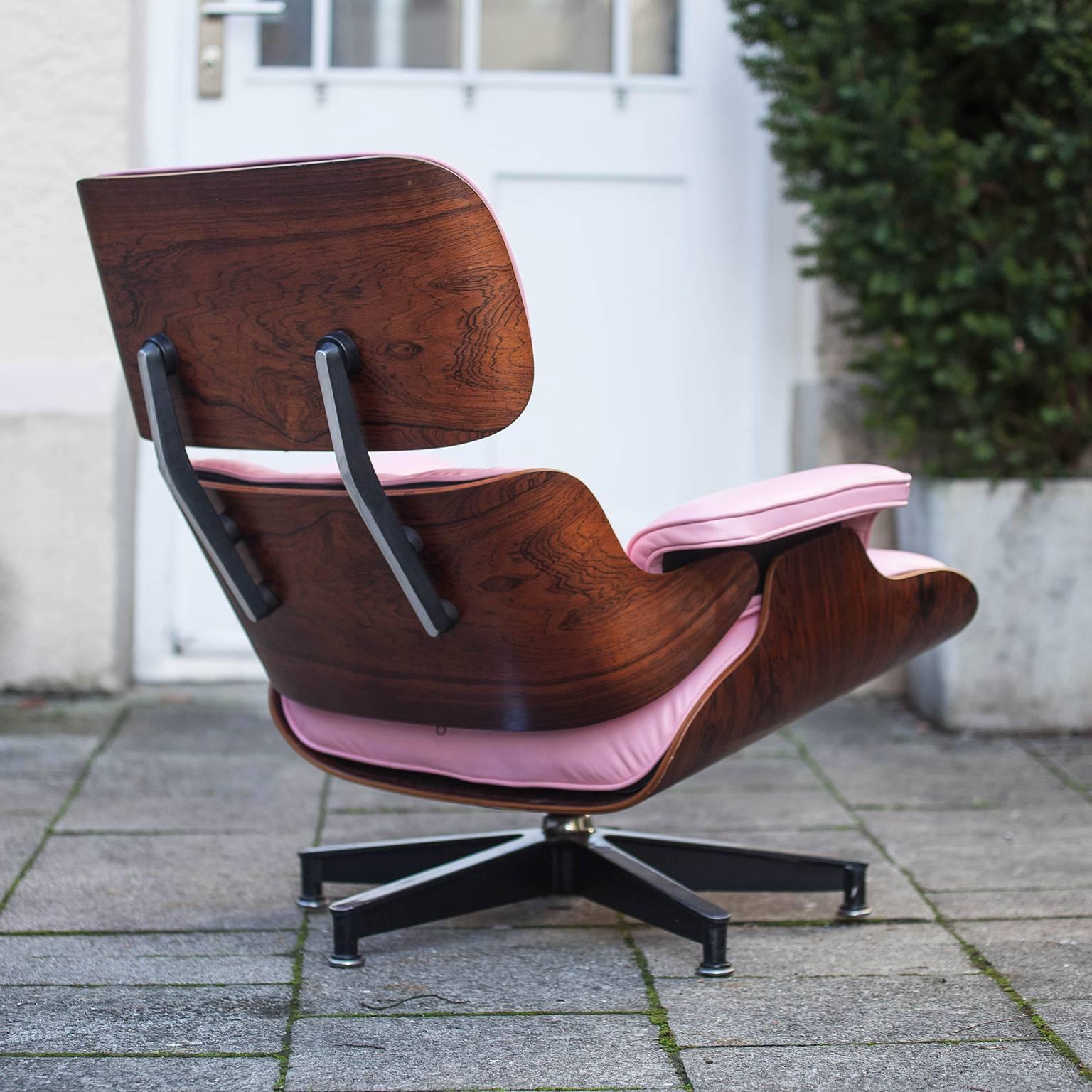 Iconic 670 lounge chair with ottoman by Charles and Ray Eames for Herman Miller. This chair is in pink new leather with a lightly grained rosewood veneer. Condition is excellent.