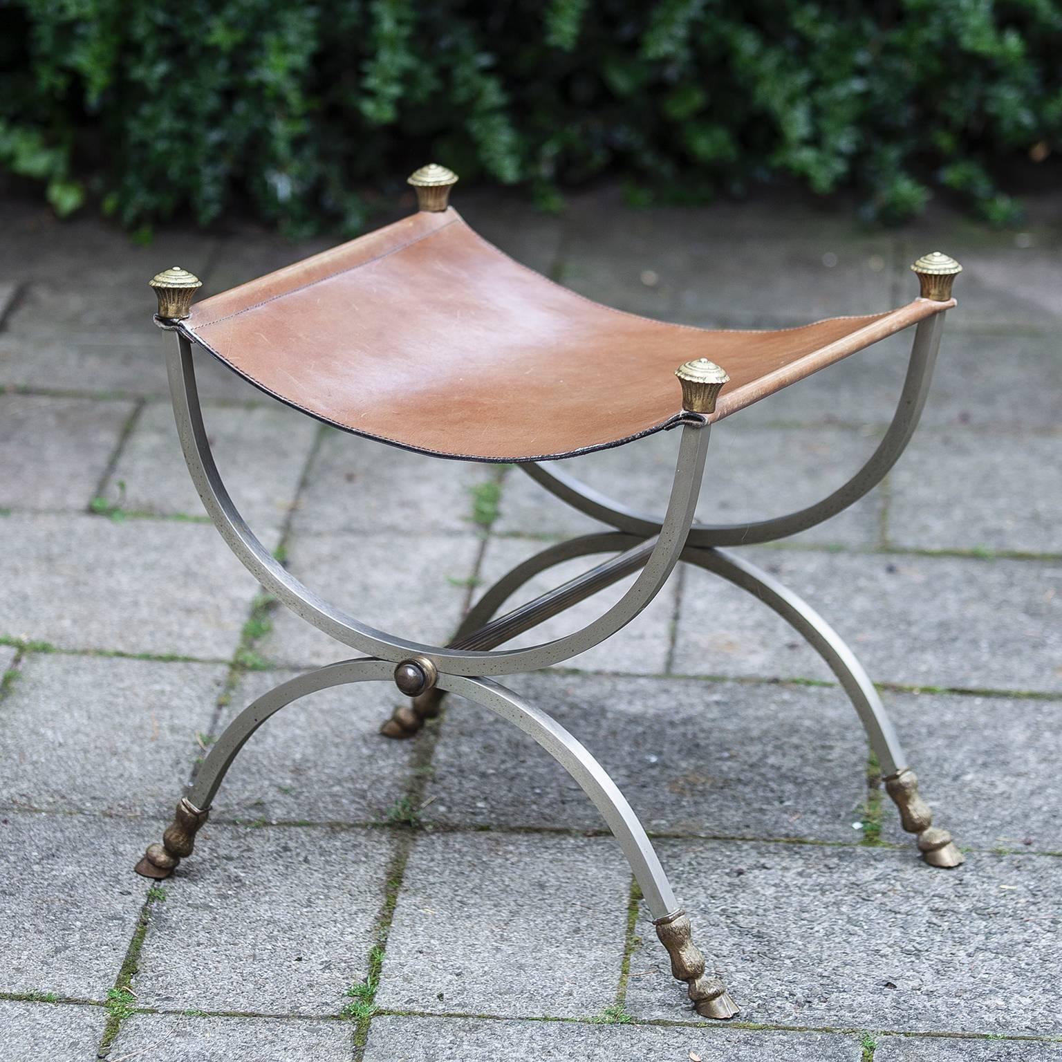 Maison Jansen sling seat stool. Original brown leather seat brushed nickel over steel frames with brass horse feets and finials. Stamped Italy on underside of feet.
