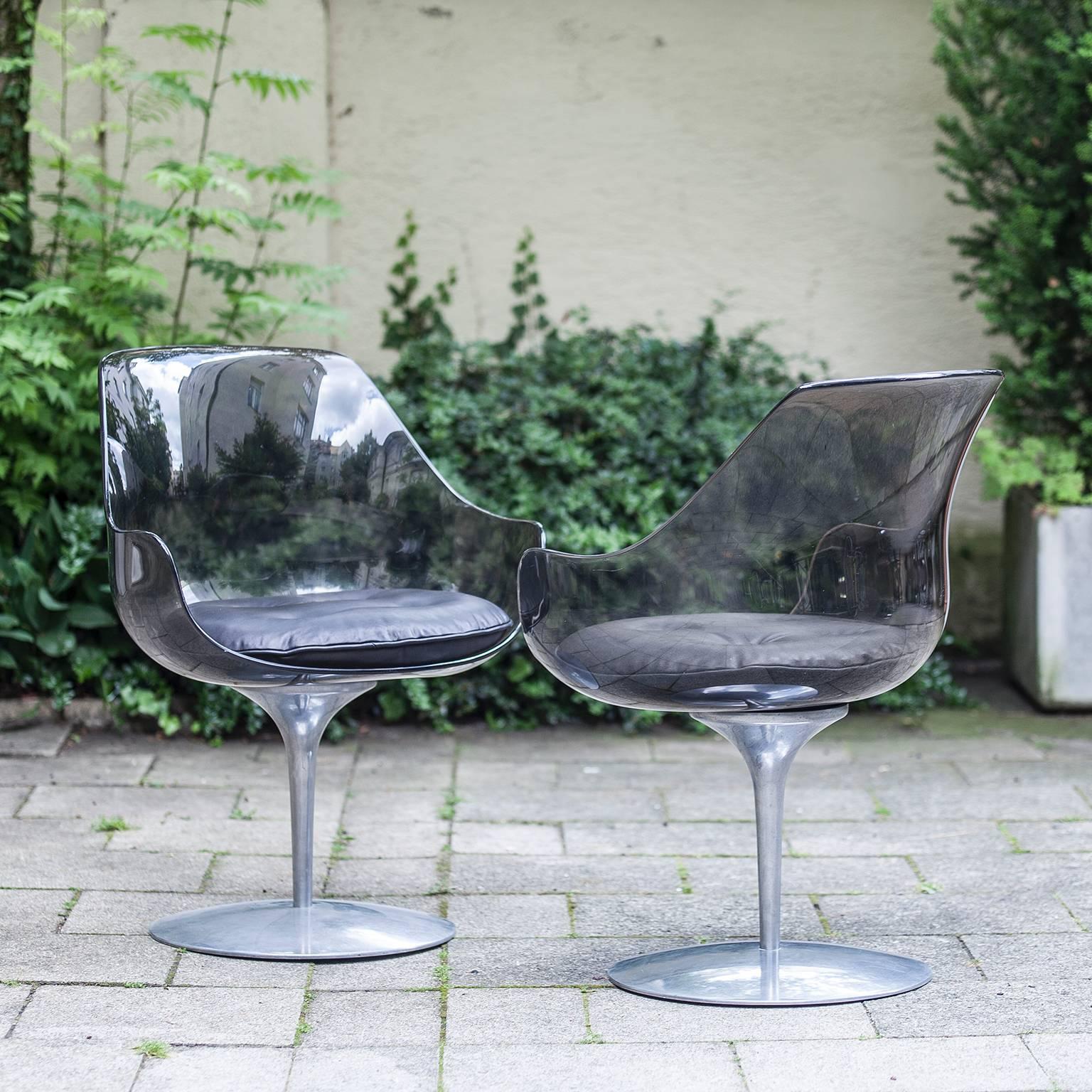 Set of two champagne chairs by Erwin & Estelle Laverne for Formes Nouvelles, on aluminum swivel pedestals with upholstered black leather seat pads and brown grey plexiglass, cast manufacturer's marks, USA, 1962.
                 