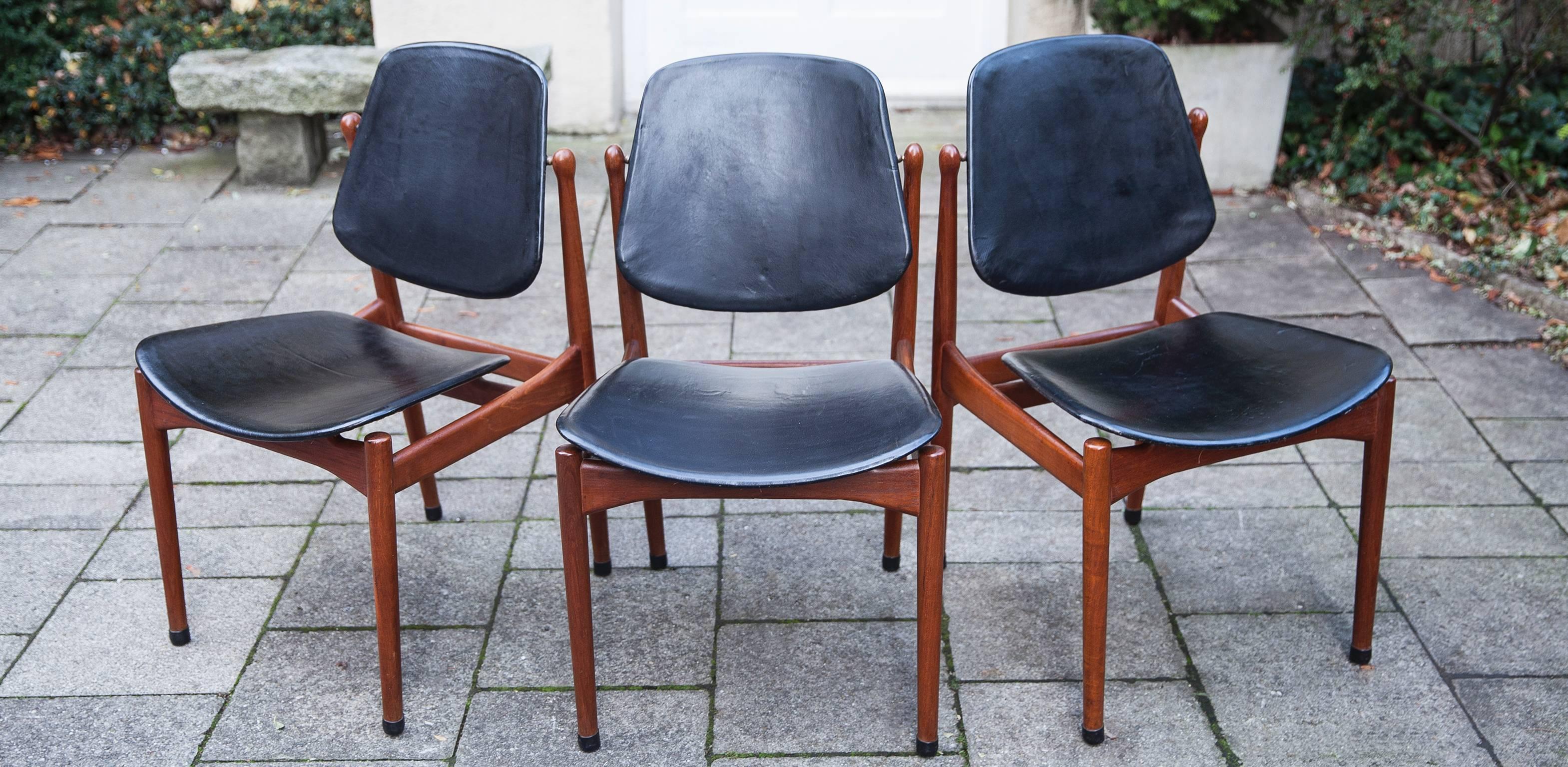 Arne Vodder Danish modern solid teak dining chairs made by France and Son of Denmark from 1957. Markers label with brass medallions and embossed insignia. The tilting black leather backs cradle the body for a very comfortable seating position.