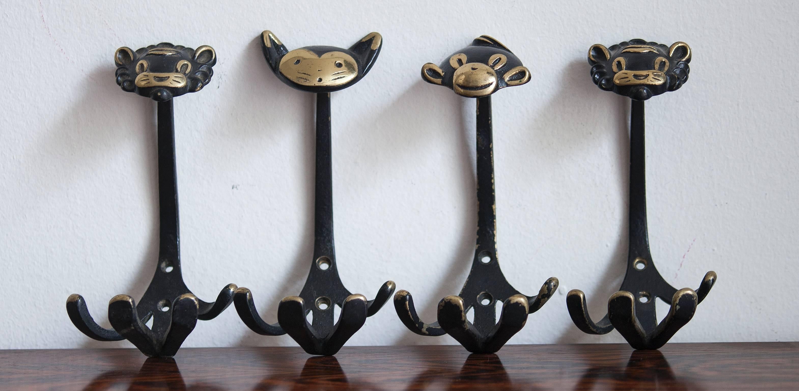 A set of 11 Austrian modernist brass wall coat hooks, displaying a three lions, three cats, a cow, two monkeys, a donkey and a rabbit. A very humorous design by Walter Bosse, executed by Hertha Baller Austria in the 1950s. Made of black finished
