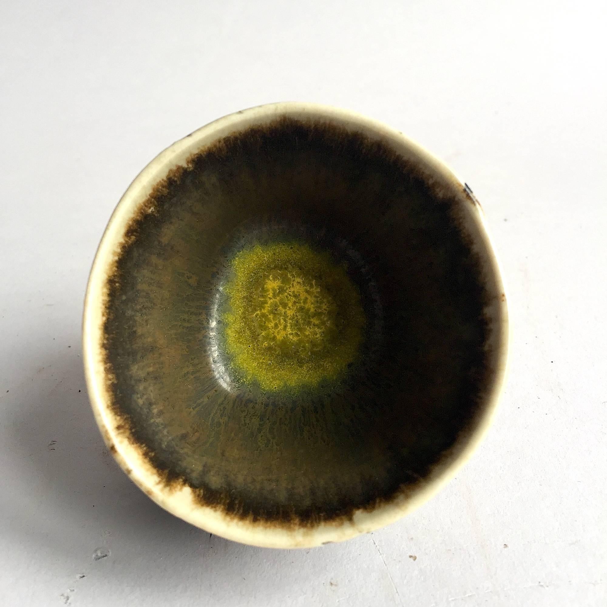 Axel Salto, Denmark.

Small stoneware bowl from Axel Salto in brown, dark green and yellow with fruits and leaves in relief. Signed 