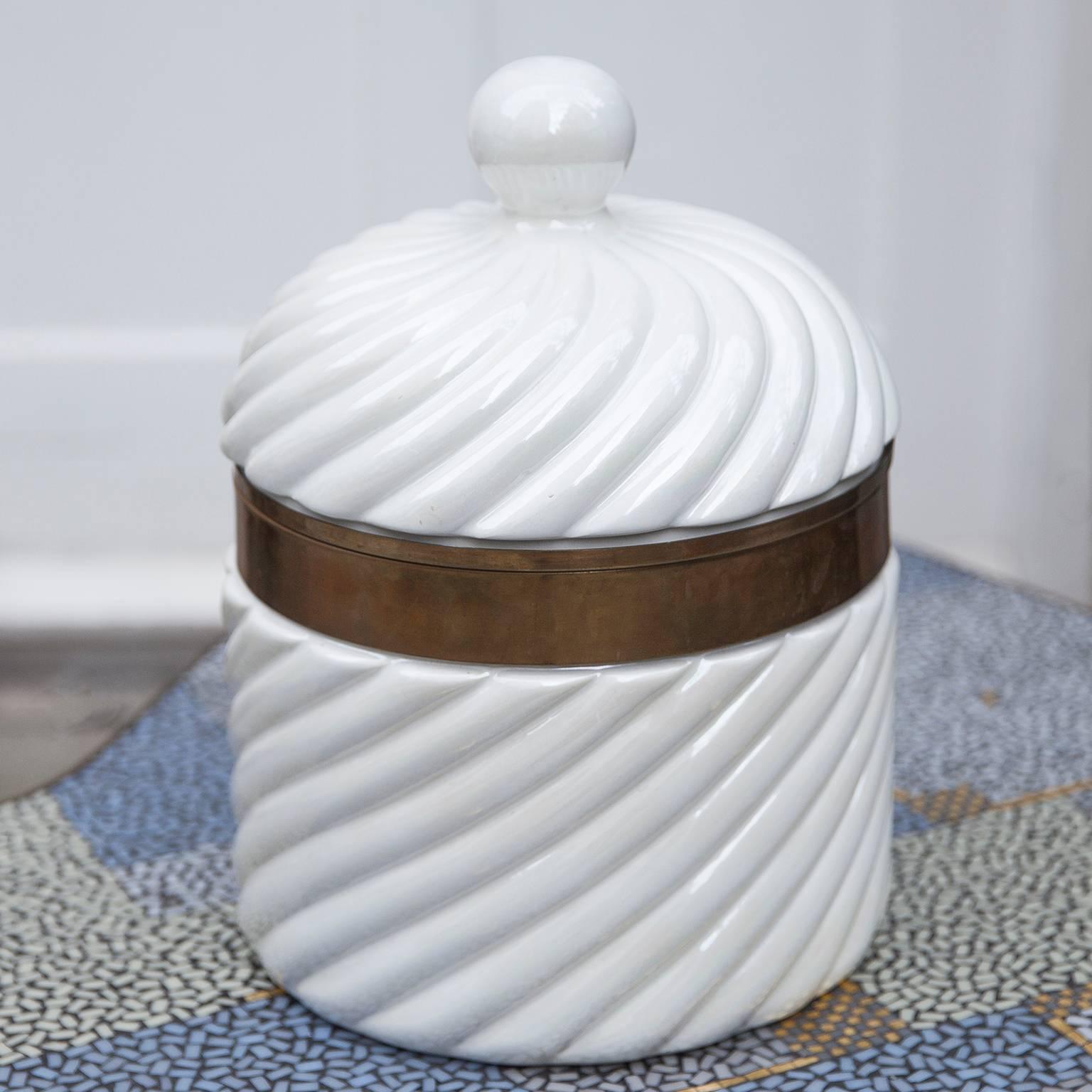 Wonderful porcelain ice bucket by the Italian Designer Tommaso Barbi in white color. The brass ring and the porcelain is in excellent condition. The size of this piece gives great presence, a statement for Hollywood Regency style.
Signed on the