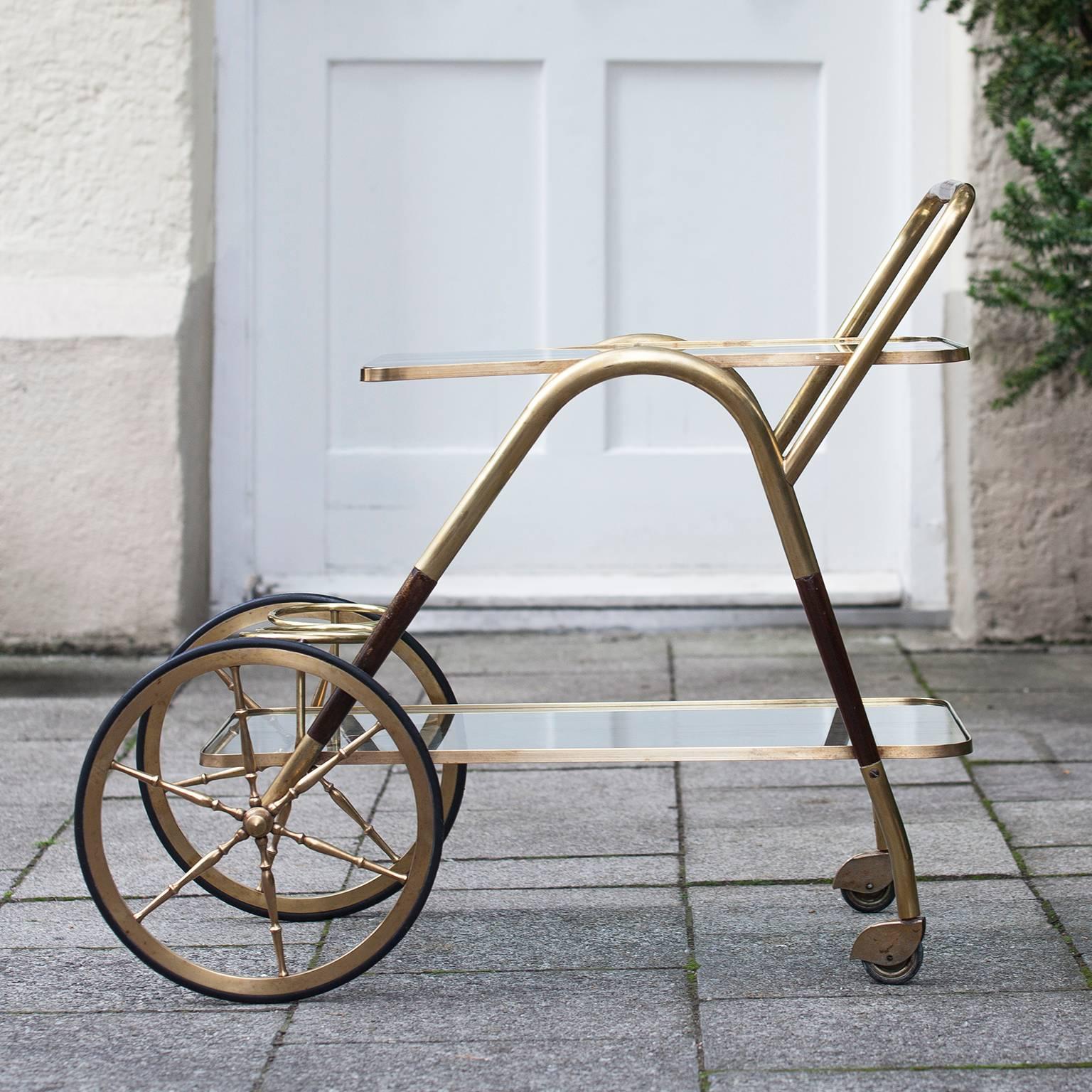 An all original bar or serving cart by Cesare Lacca from Italy of the 1950s.
Manufactured in wood and polished brass. Two tiers with clear glass and a holder for three bottles at the bottom. The wheels are also original and in good working