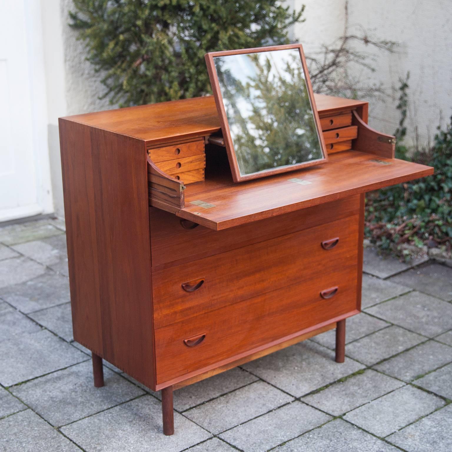 Peter Hvidt and Orla Mølgaard-Nielsen designed this handsome gentleman's dresser for J. Jacobsen and Sonner. The teak case sits on plinth base and features exposed finger joinery and sculpted drawer pulls. There are three drawers. Above them, the