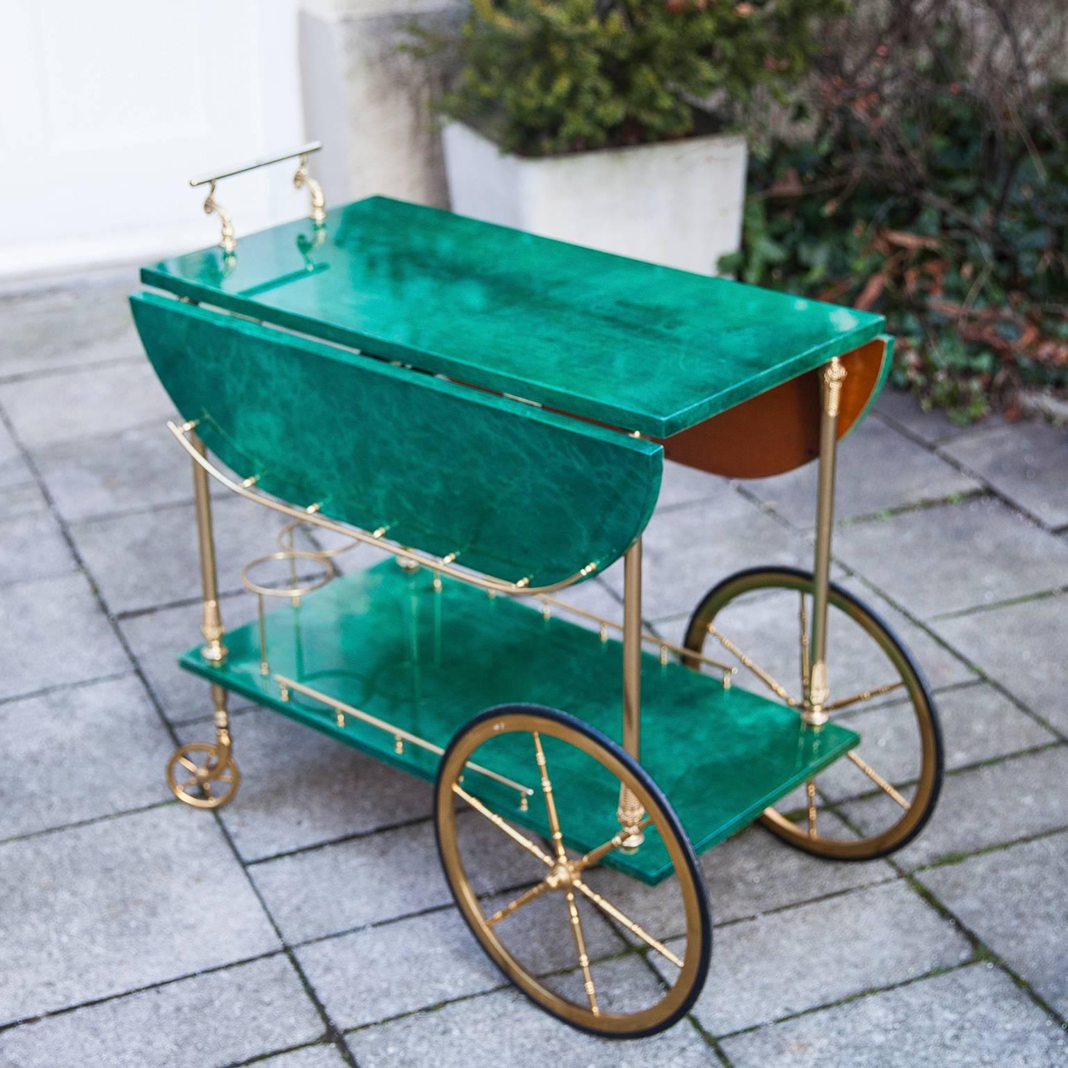 Elegant lacquered goatskin bar cart by Aldo Tura in emerald green. The sides can be fold up. The goatskin shows a stunning deep tone, which is in a very nice contrast with the elegant, well designed brass details. Manufactured in Italy,