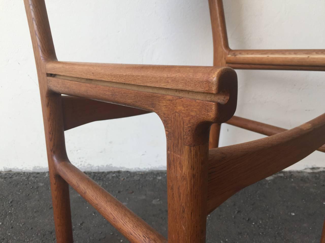 A set of four patinated oak side chairs, front legs with visible joints, seat and back stretched with brown painted colored leather. Manufactured by Mikael Laursen.
 